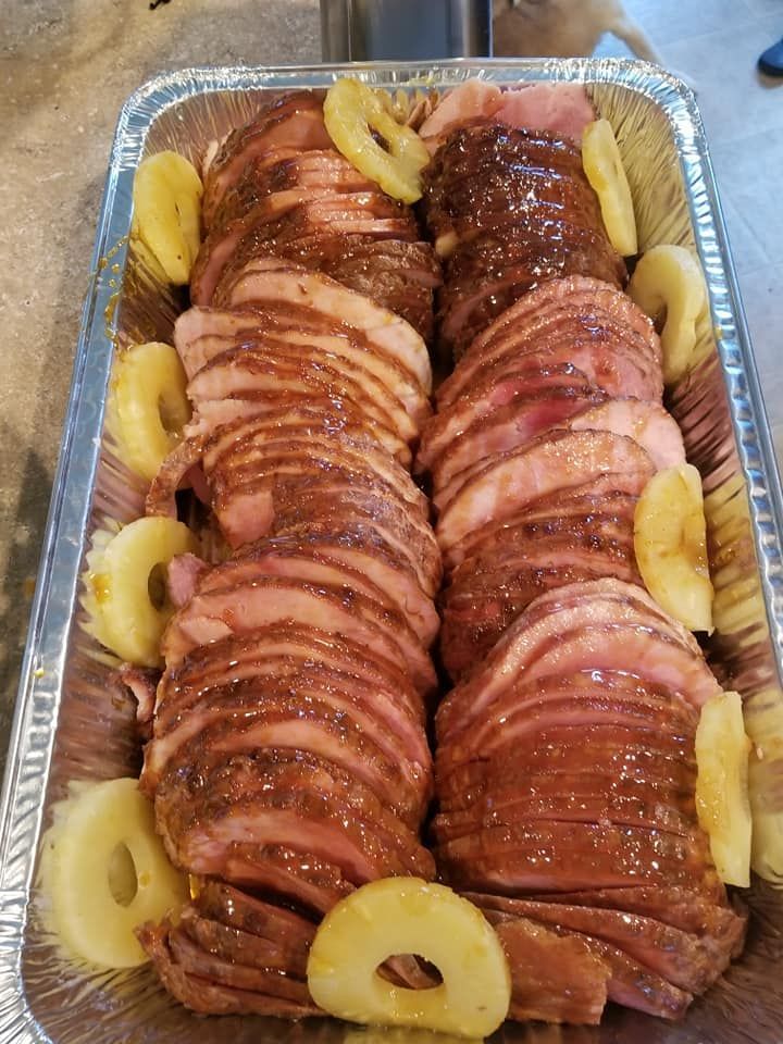 Trays of sliced glazed ham topped with pineapple rings, arranged for serving