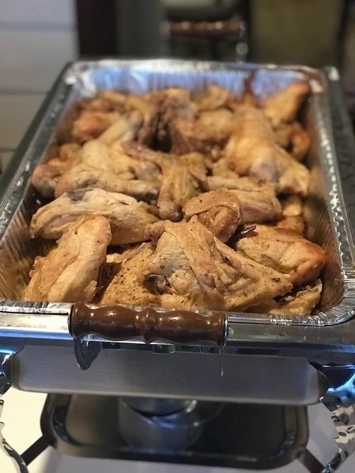 Tray of cooked chicken wings warming on a stovetop burner