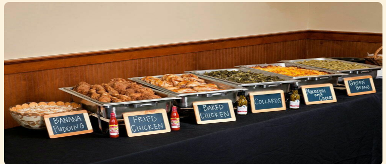 Buffet table with trays of breakfast pastries and labeled dishes on a black tablecloth
