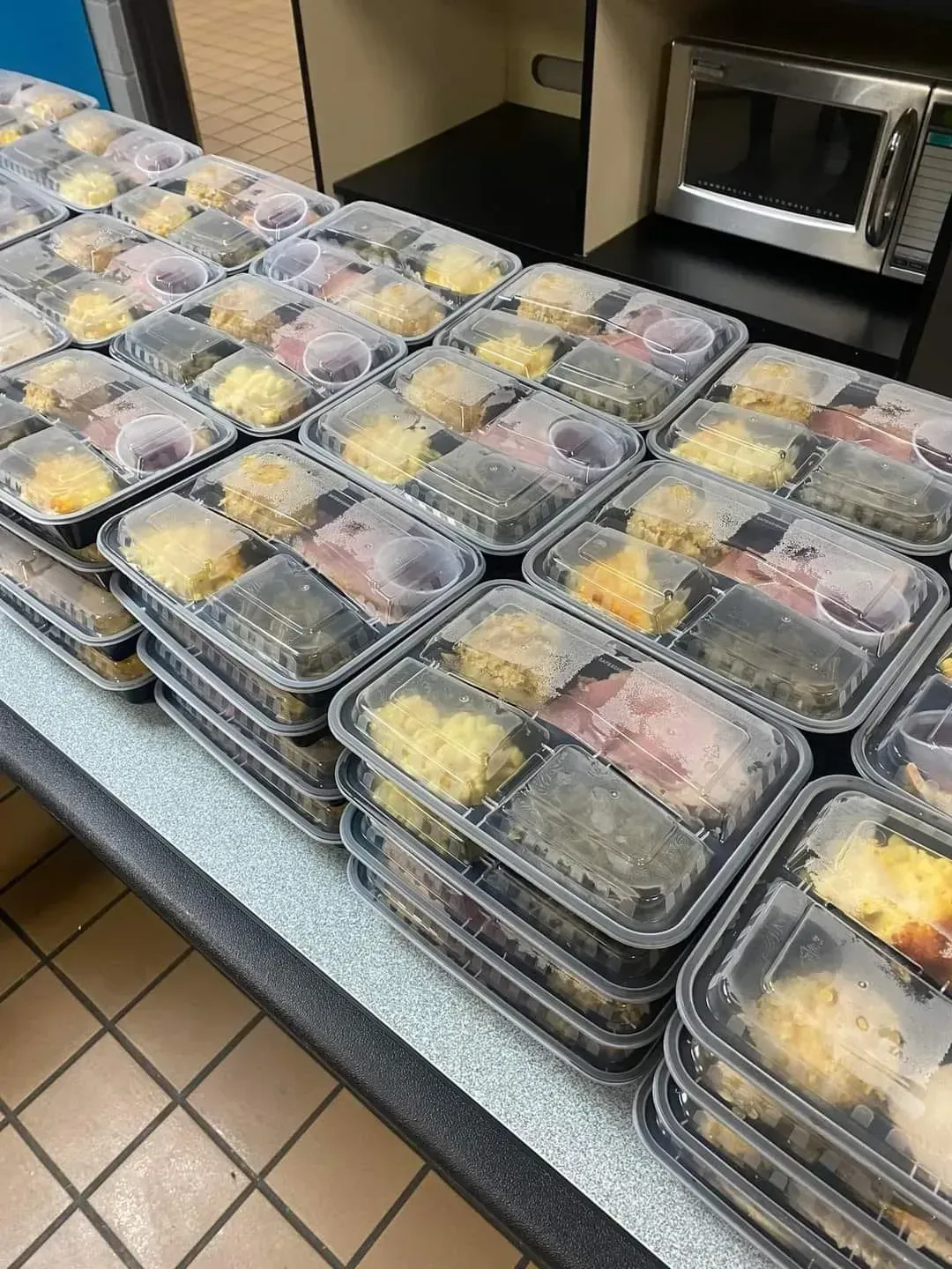 Stacked meal prep containers on a kitchen counter beside a microwave.