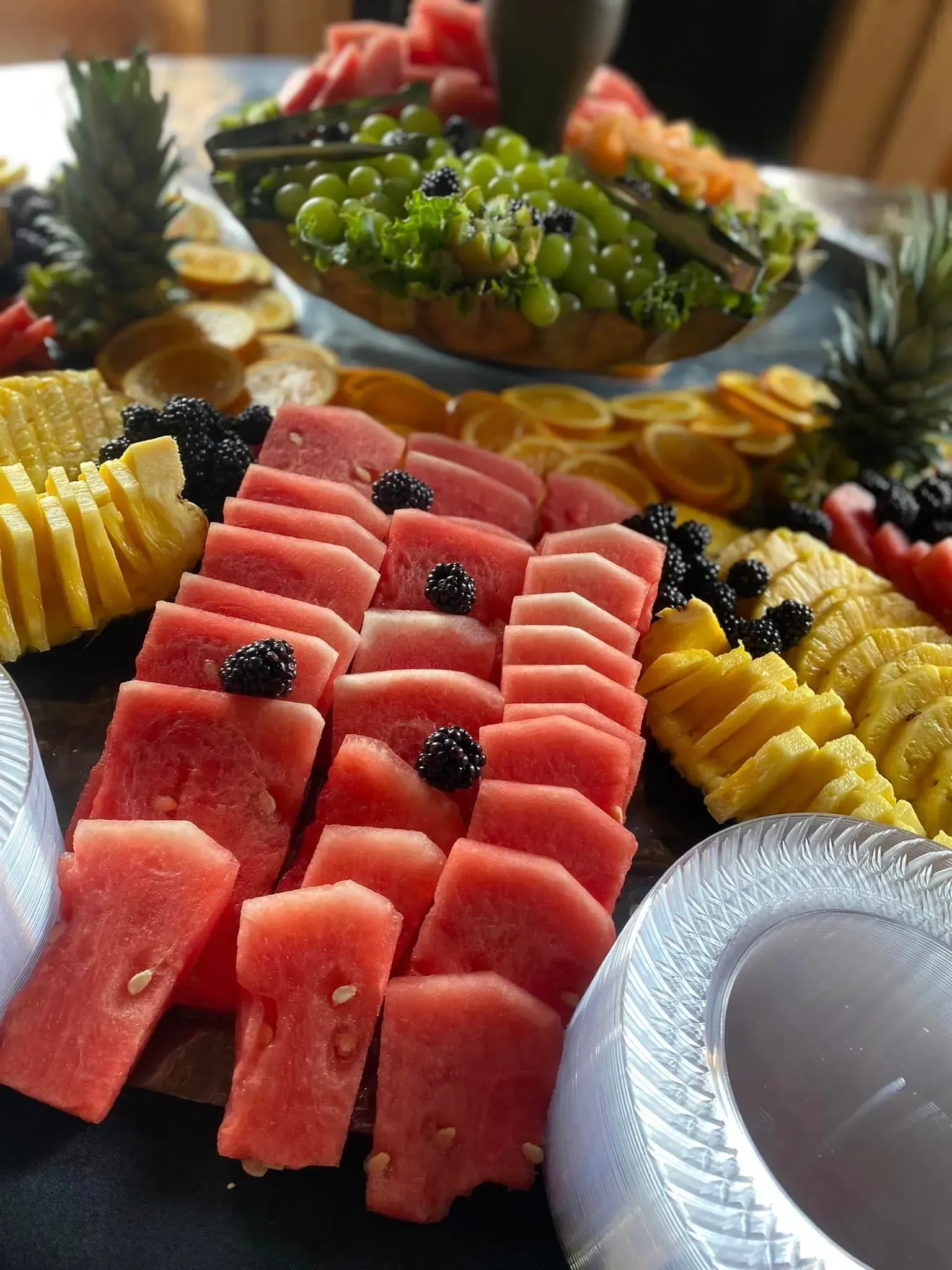 Colorful fruit platter with watermelon, pineapple, and grapes arranged on a table