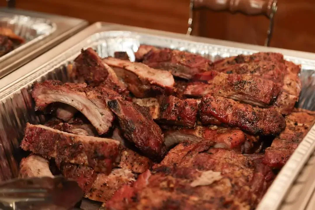 Tray of grilled ribs and barbecue meat on a foil-lined serving platter