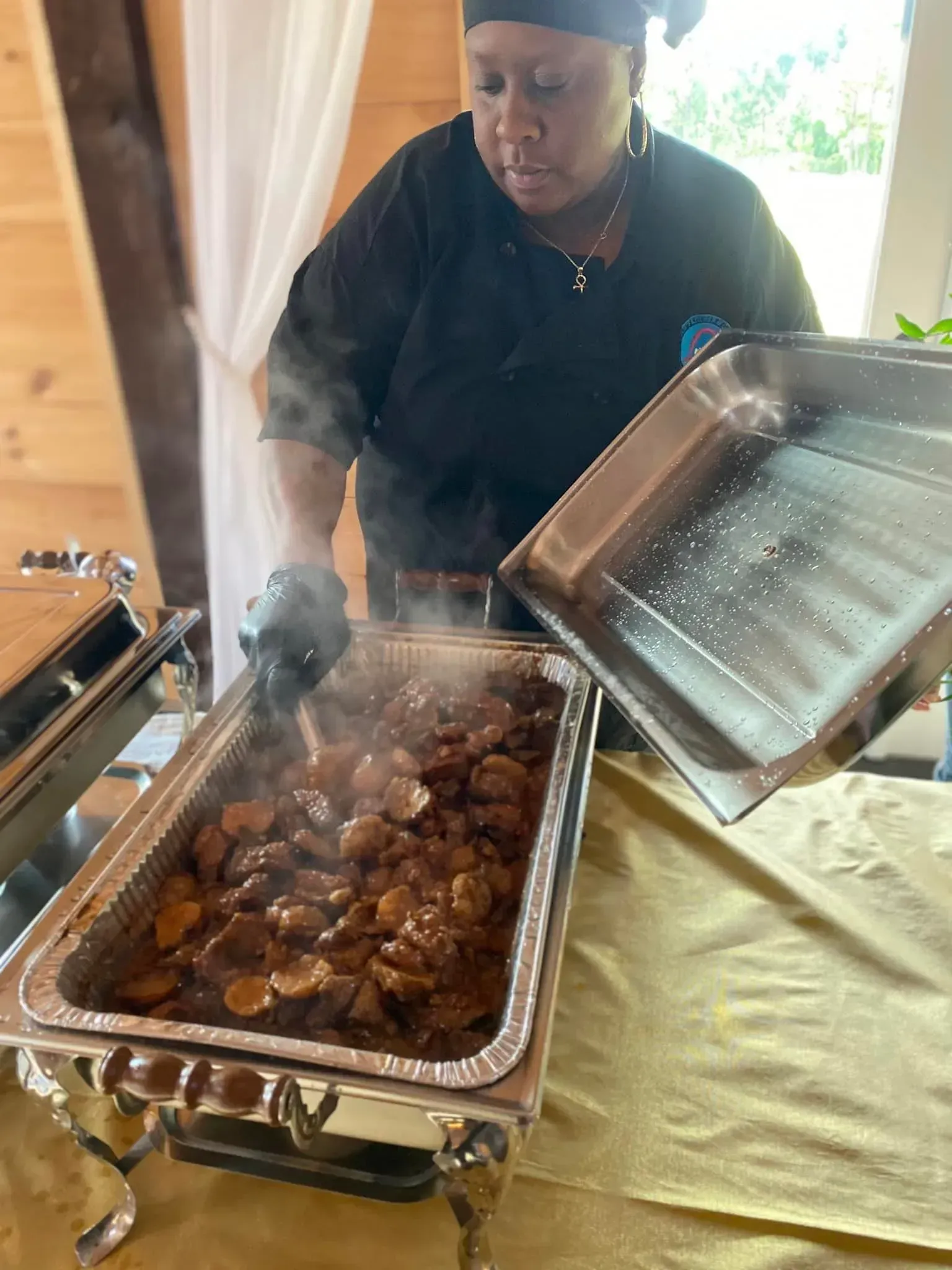 Chef serving steaming grilled meat from a chafing dish at a buffet table