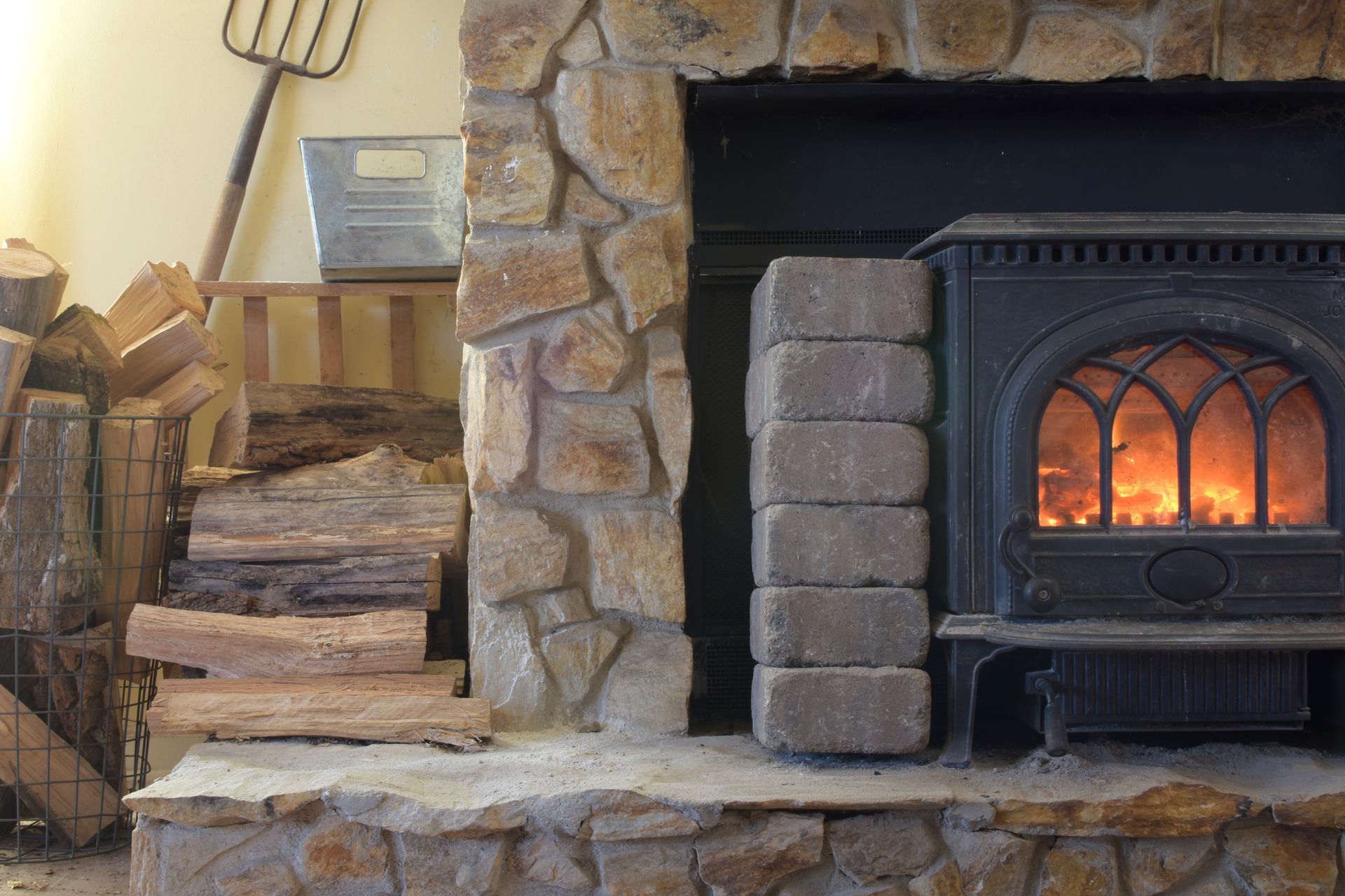 A Wood-burning Stove With a Glowing Fire Sits Next to a Stack of Firewood — The Flue Pro In Huntingfield, TAS