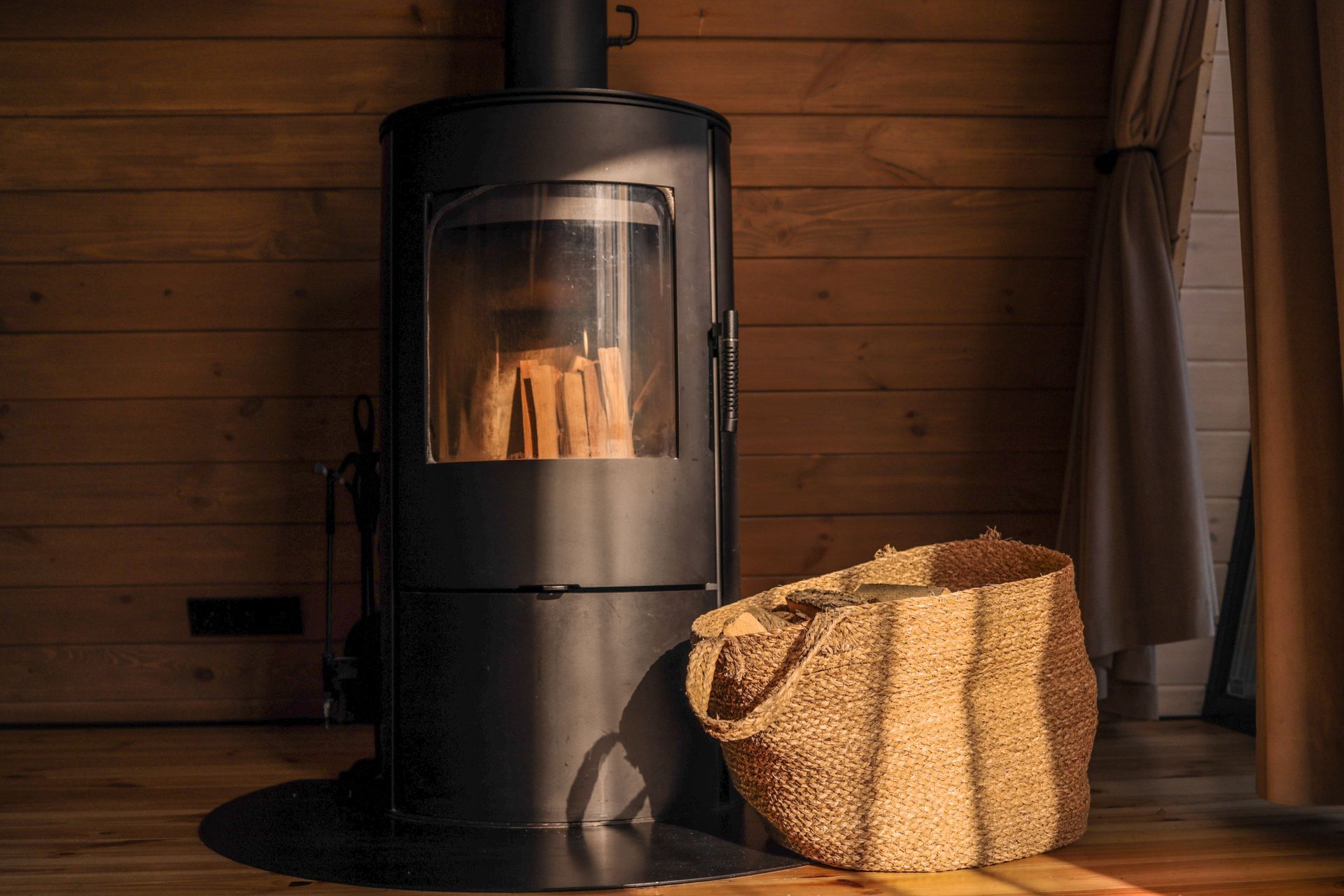 A Black Cylindrical Wood Stove Sits Against a Horizontal Wood-plank Wall — The Flue Pro In Huntingfield, TAS