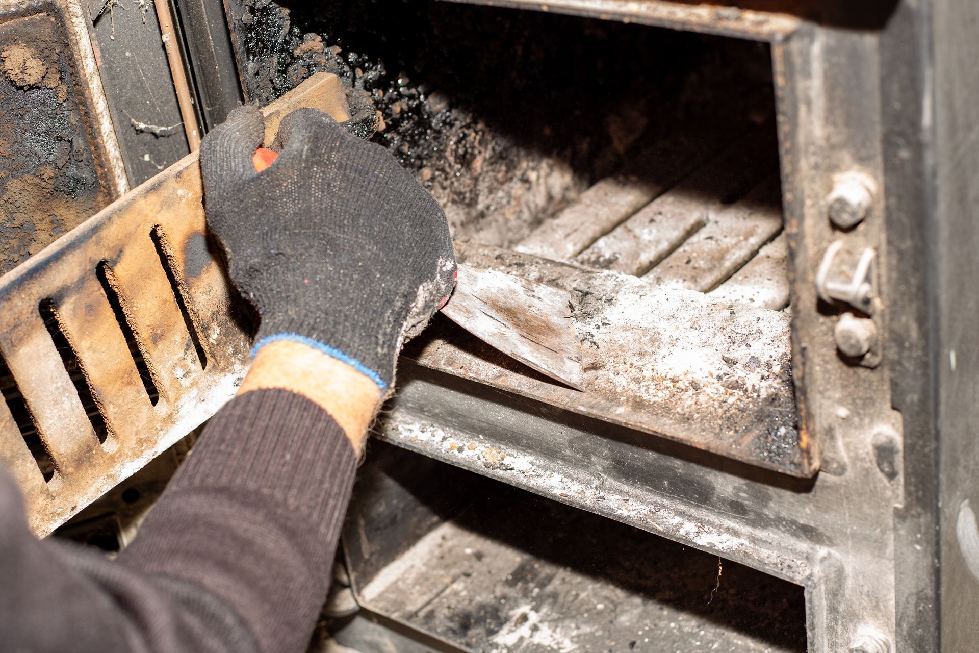 A Hand Wearing a Protective Glove Using a Tool to Clean Soot and Ash — The Flue Pro In Huntingfield, TAS