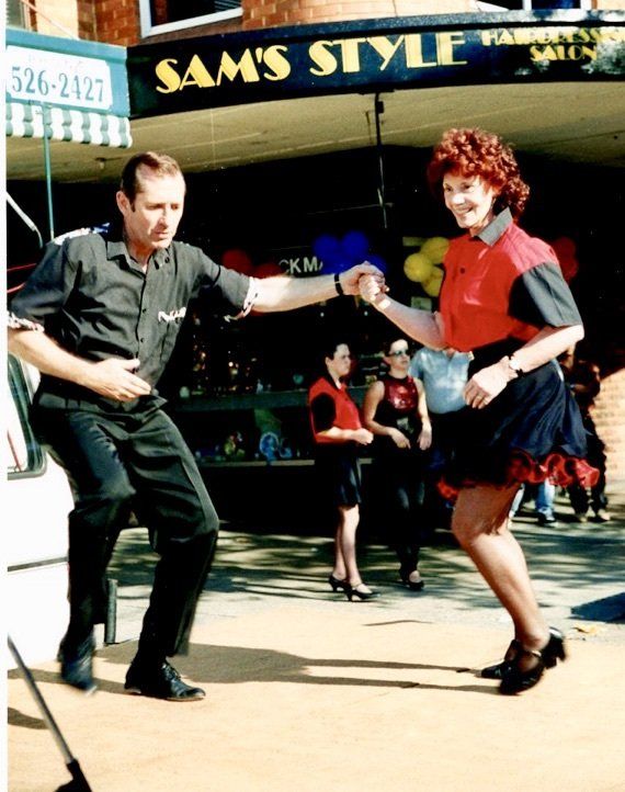 A man and woman are dancing in front of sam 's style
