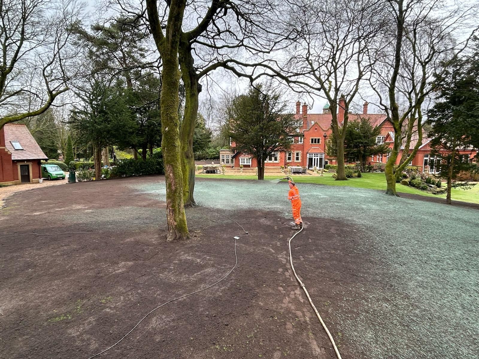 A CDTS operative hydroseeding a private lawn using hoses to access tricky areas.