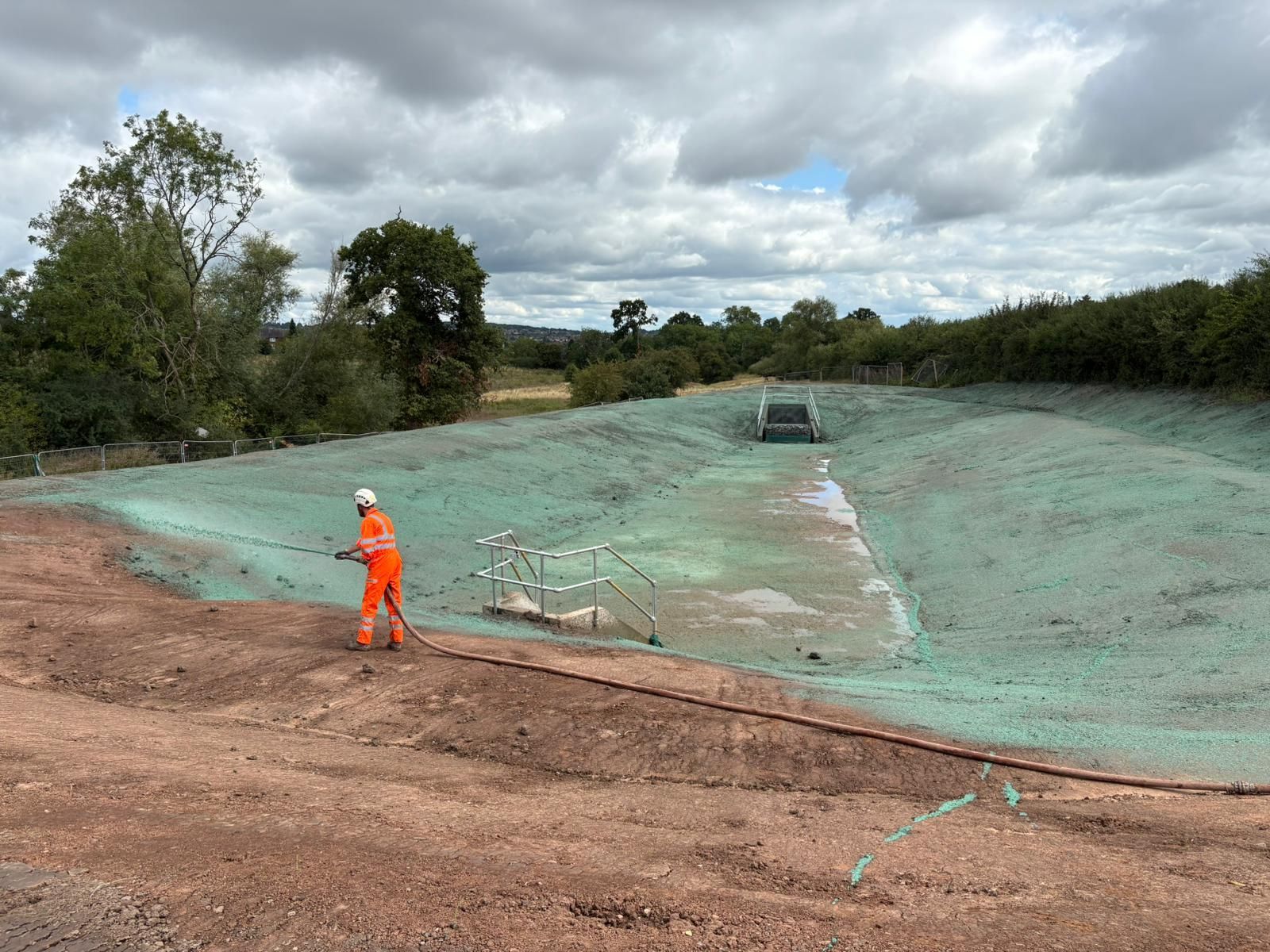 The hydroseeding of a drainage feature for Landstruction. Hoses used to give operatives full access to the area.