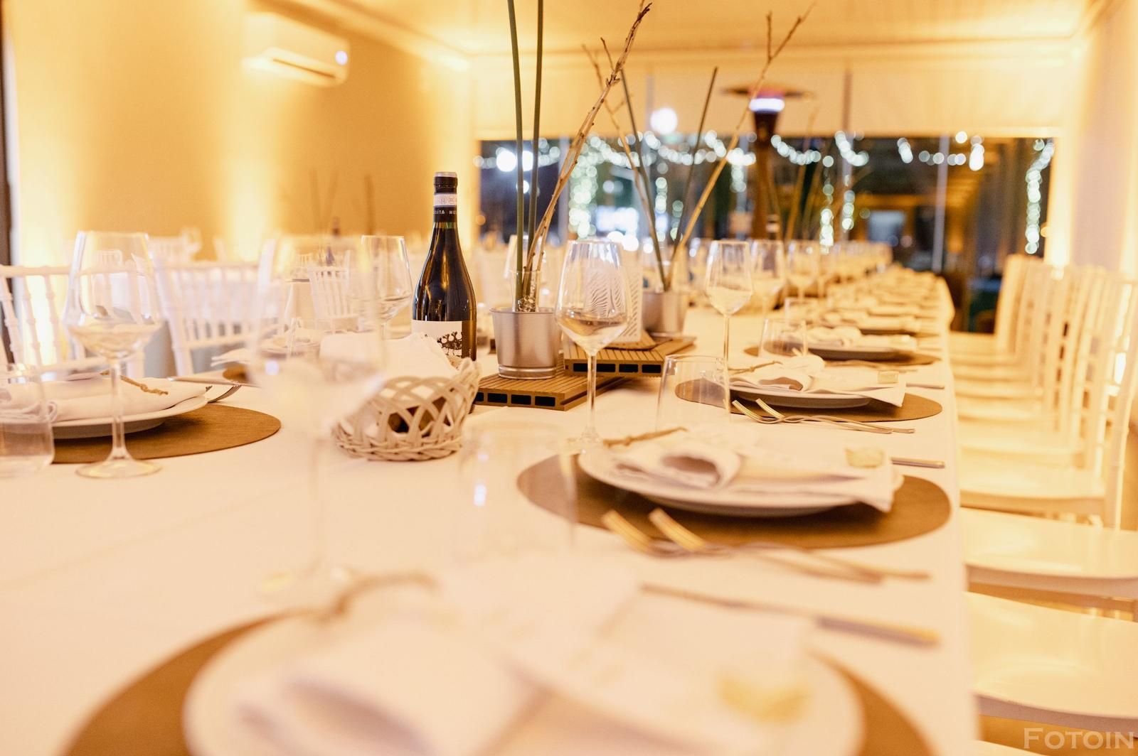 Elegante tavolo da banchetto apparecchiato con sedie e piatti bianchi in una sala da pranzo.