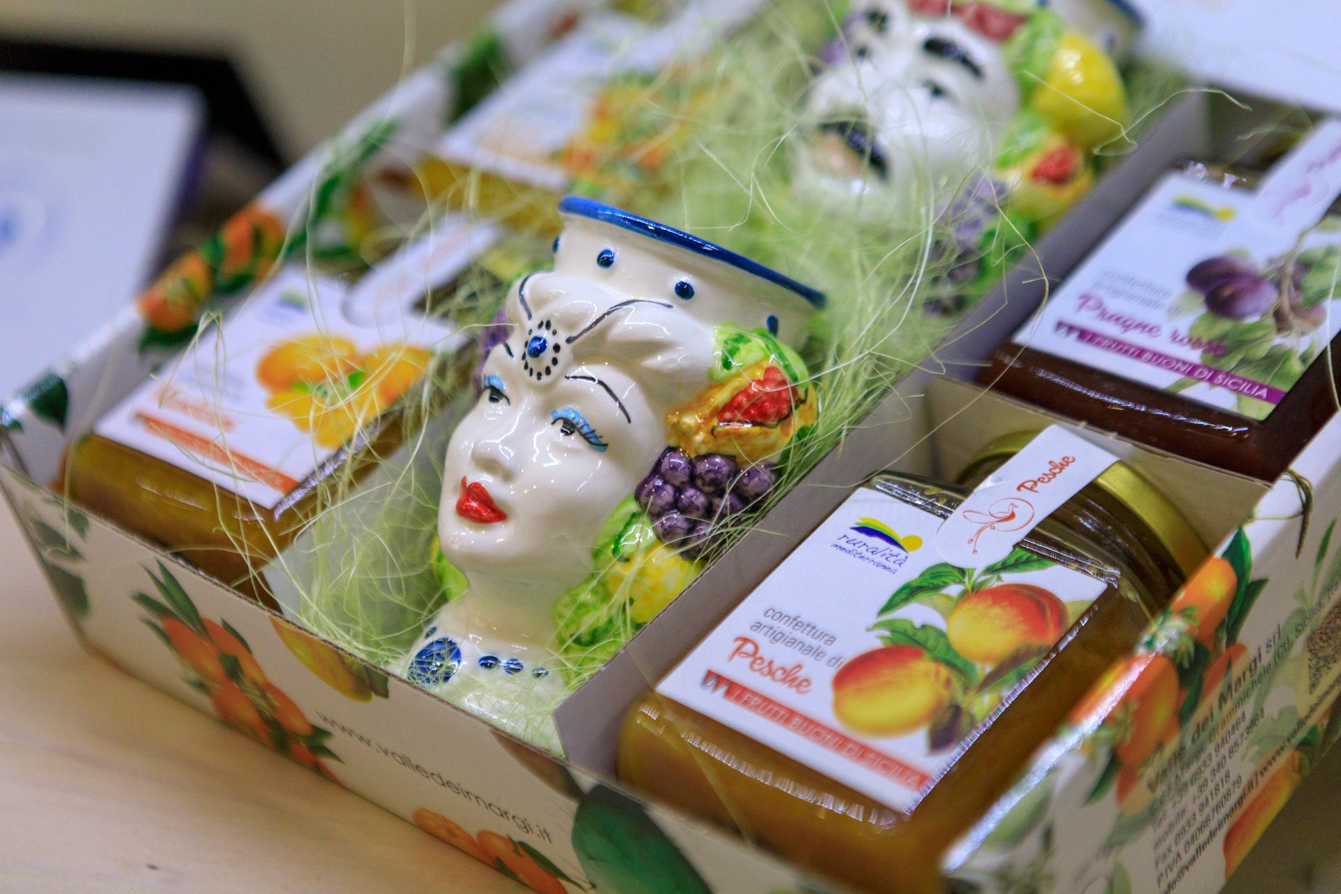 Scatole regalo con frutta e una statuetta decorativa a forma di viso disposte su un tavolo