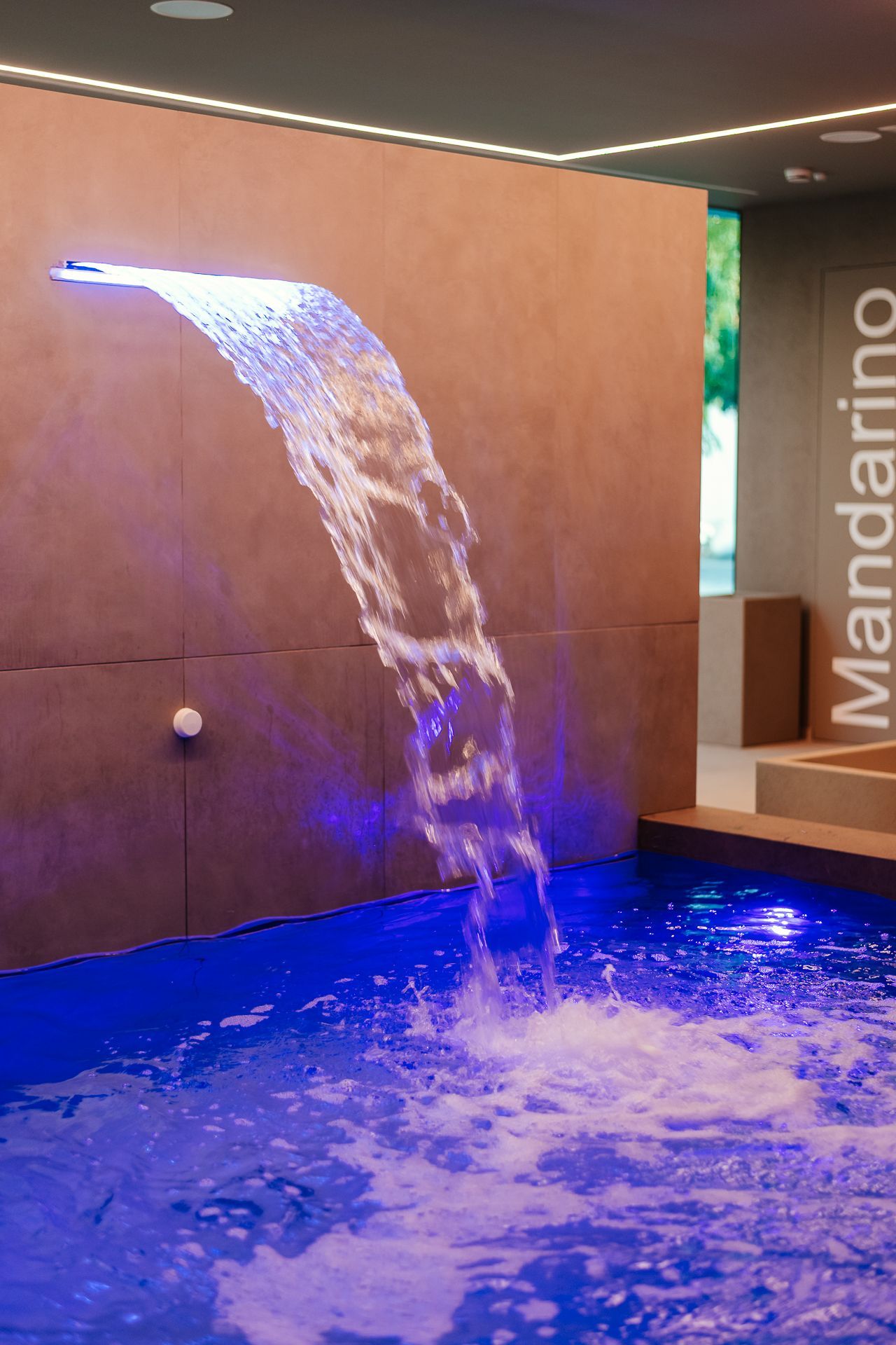 Persona che riceve un massaggio al collo su un lettino da trattamento, in un'atmosfera da spa illuminata di verde.