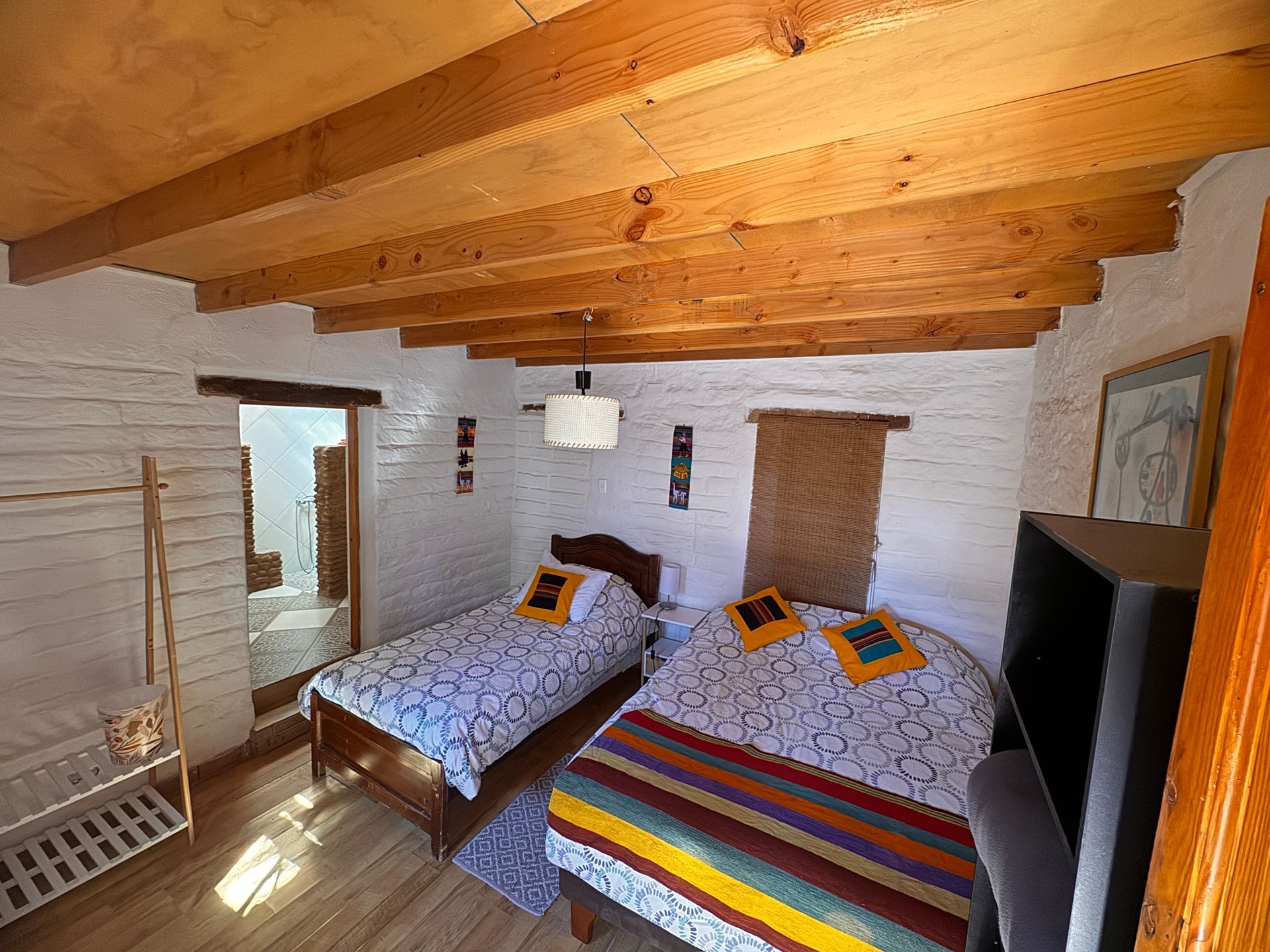 Acogedora habitación con dos camas, paredes de ladrillo blanco y techo con vigas de madera.