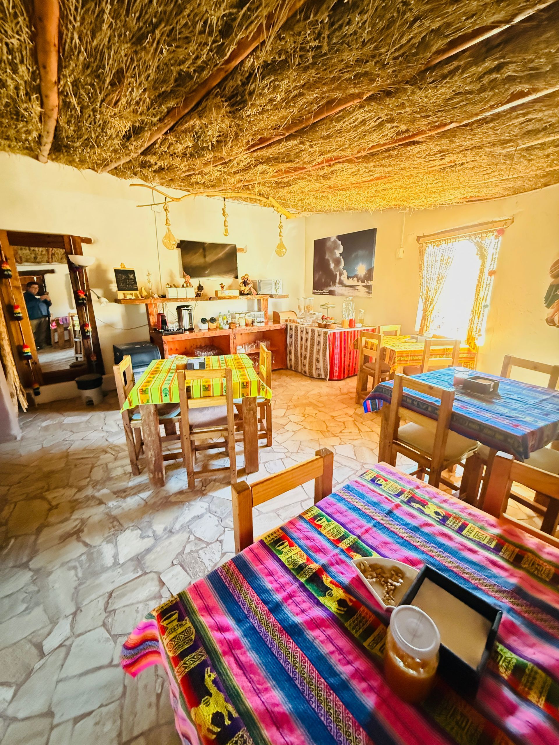 Comedor rústico con coloridos manteles tejidos, sillas de madera y luz solar cálida.