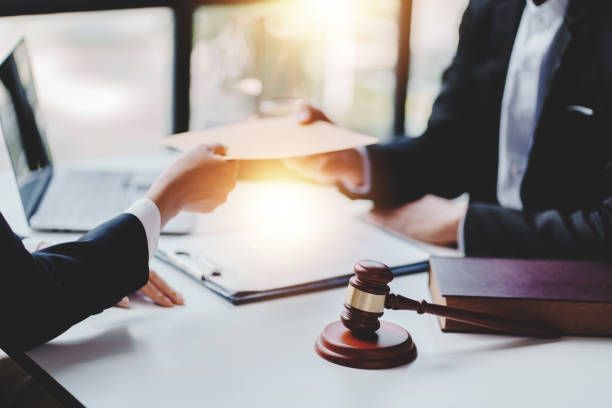 Two men are sitting at a table with a judge 's gavel and a clipboard.