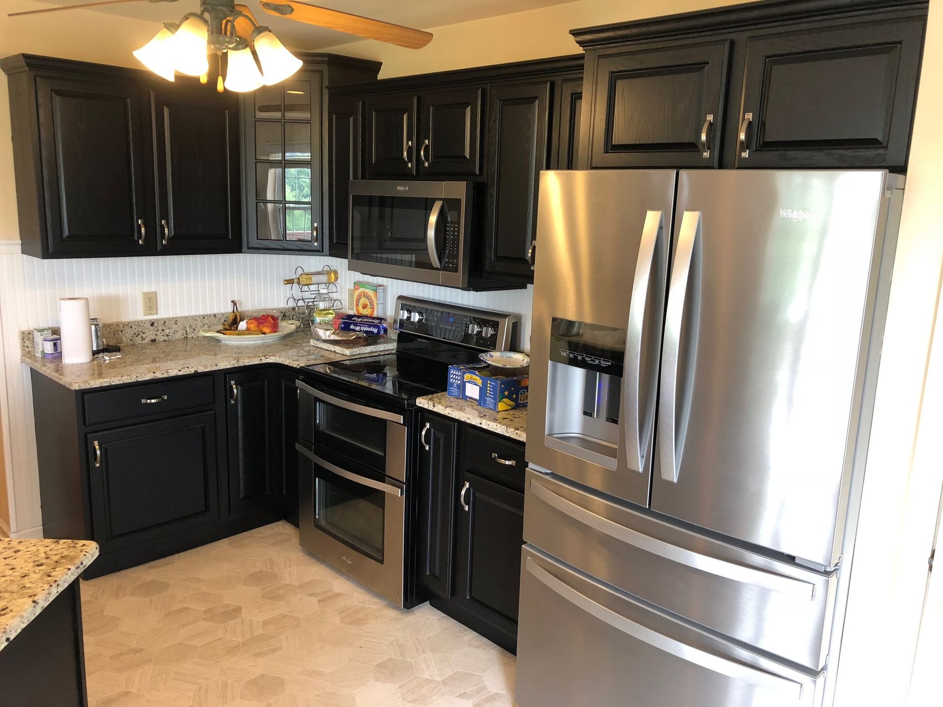 Black kitchen cabinets, stainless steel appliances, granite countertops, and a refrigerator.