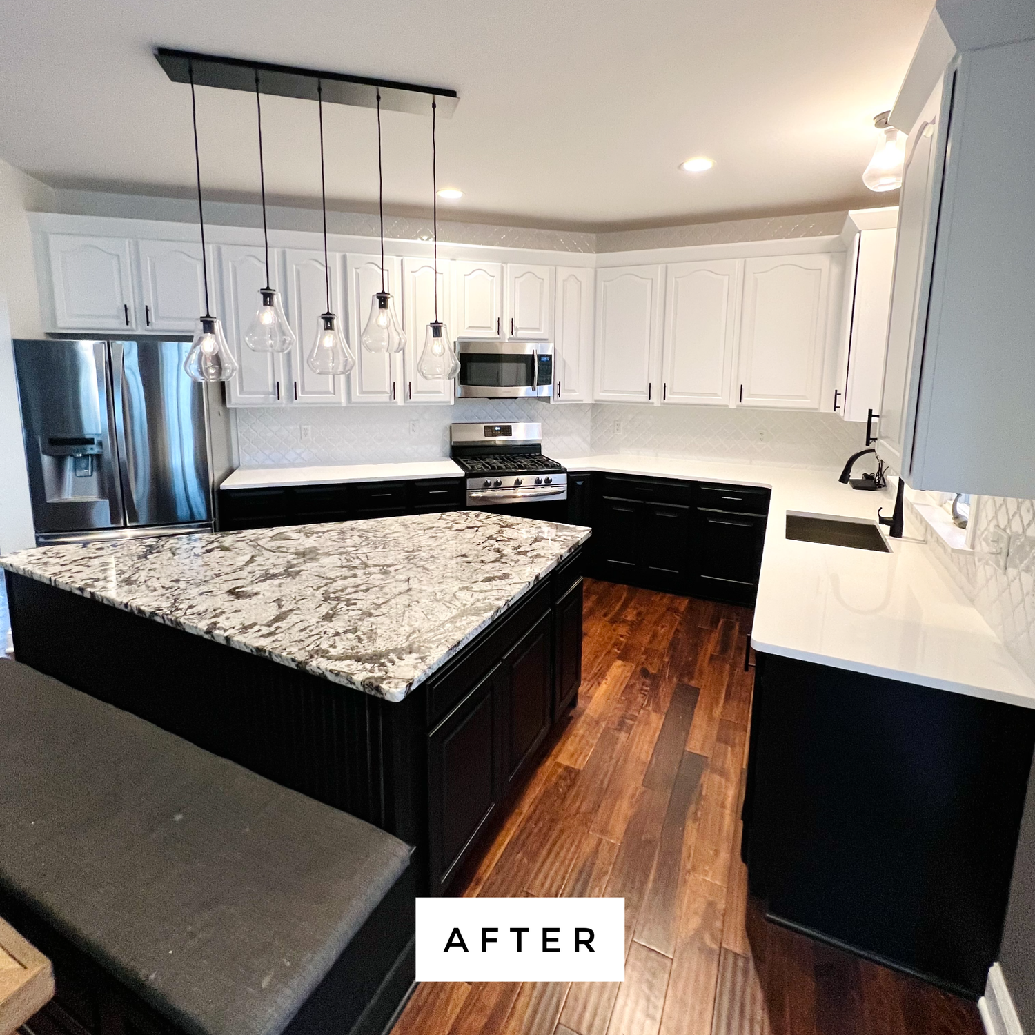Modern kitchen with white upper cabinets and black lower cabinets, island with granite countertop, hardwood floors.