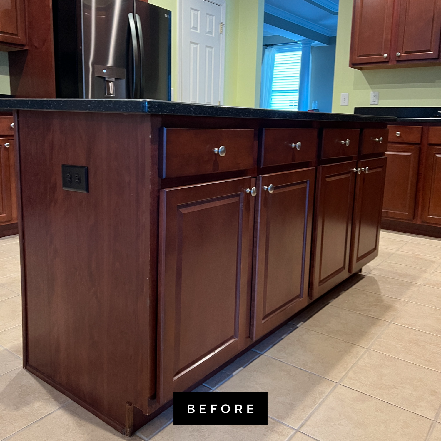 Kitchen island with dark wood cabinets, black countertop, and a power outlet.