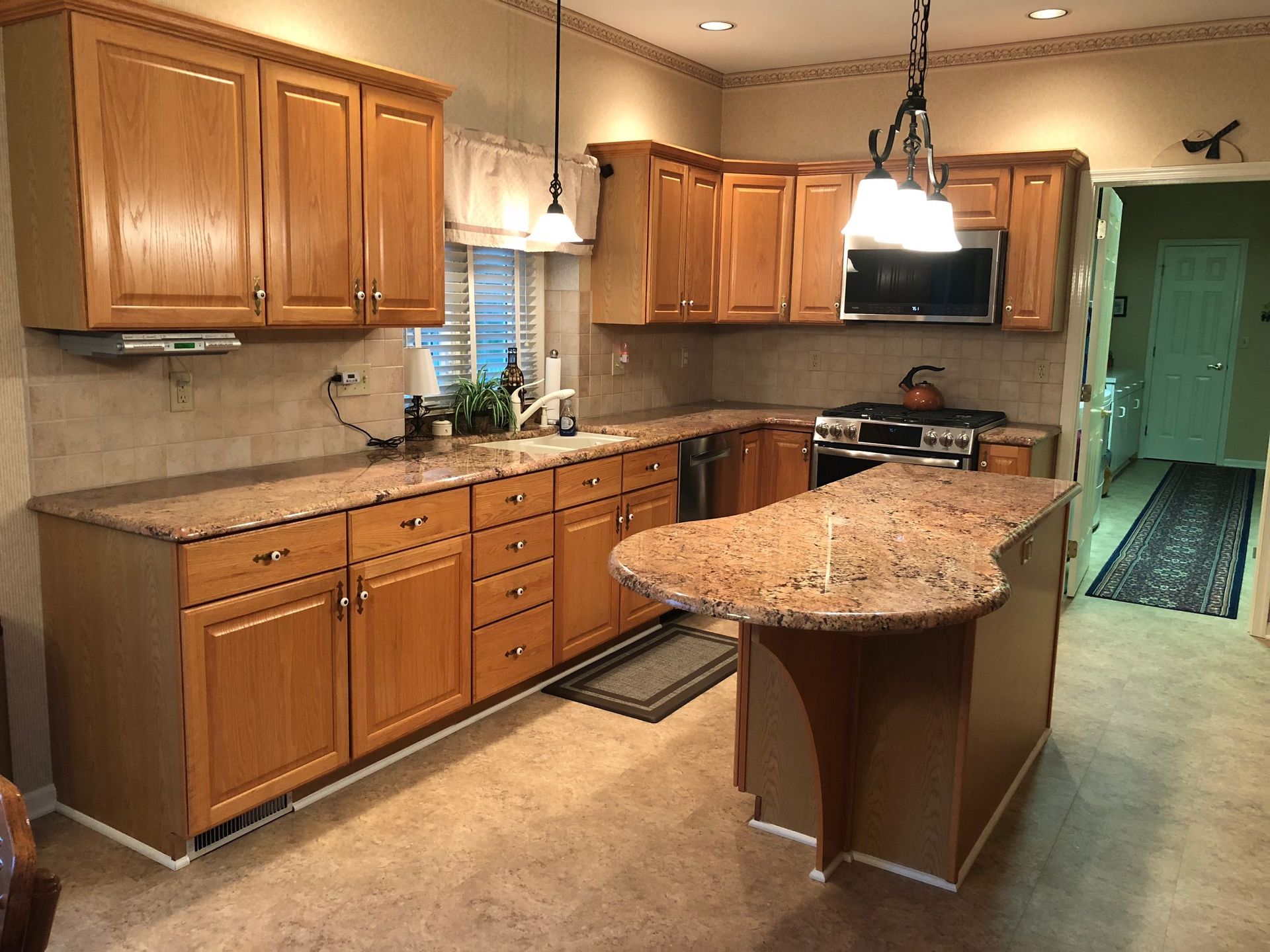 Kitchen with light brown cabinets, granite countertops, and an island.