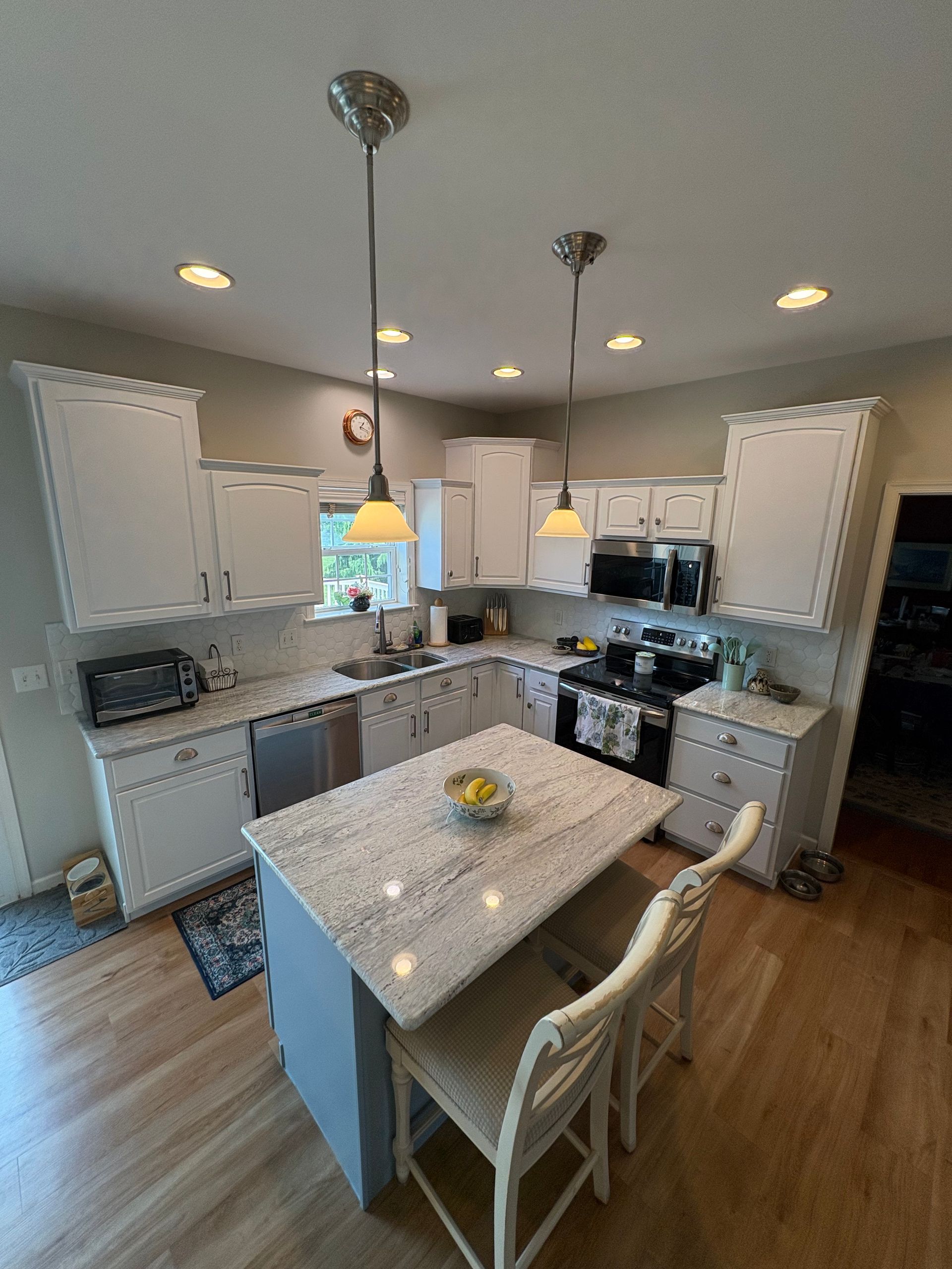 White kitchen with an island, countertops, and two pendant lights.