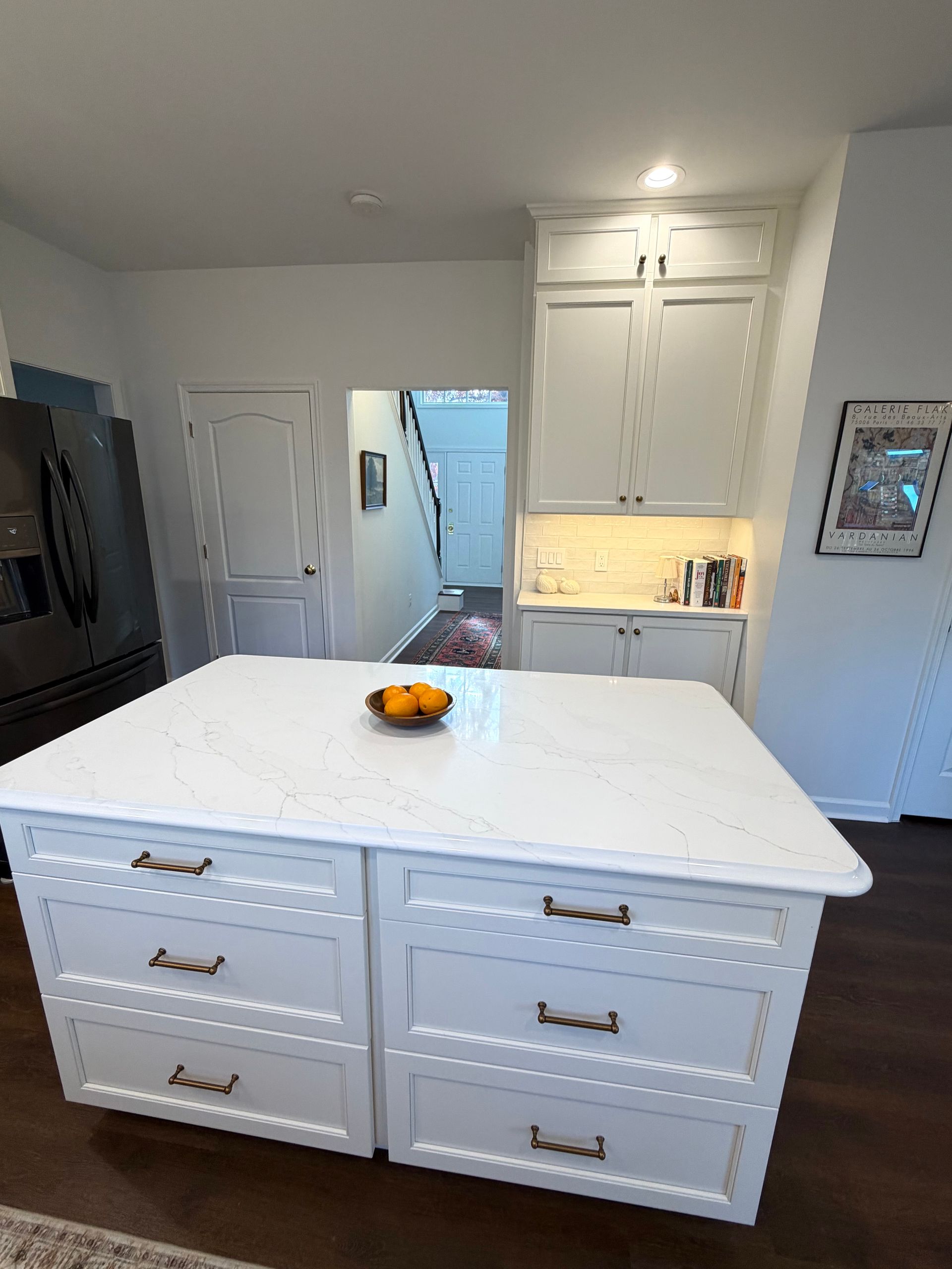 White kitchen island with drawers, oranges on countertop, and cabinets.