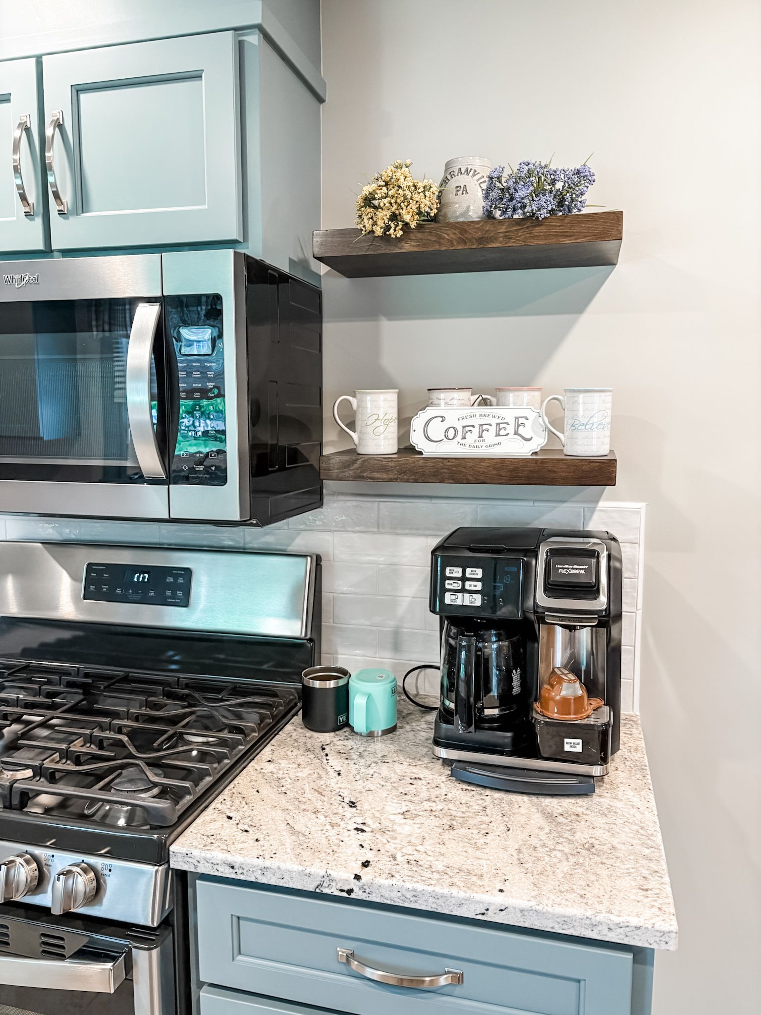 Kitchen coffee station with a microwave, shelves holding mugs, and a coffee maker.