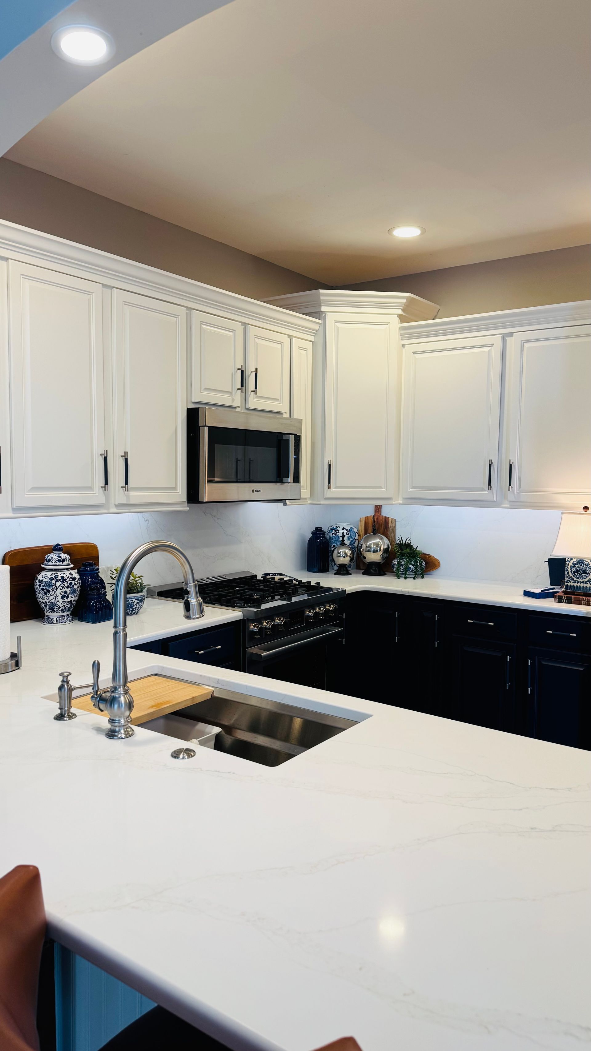 White and black kitchen with stainless steel appliances, overhead cabinets and white countertops.