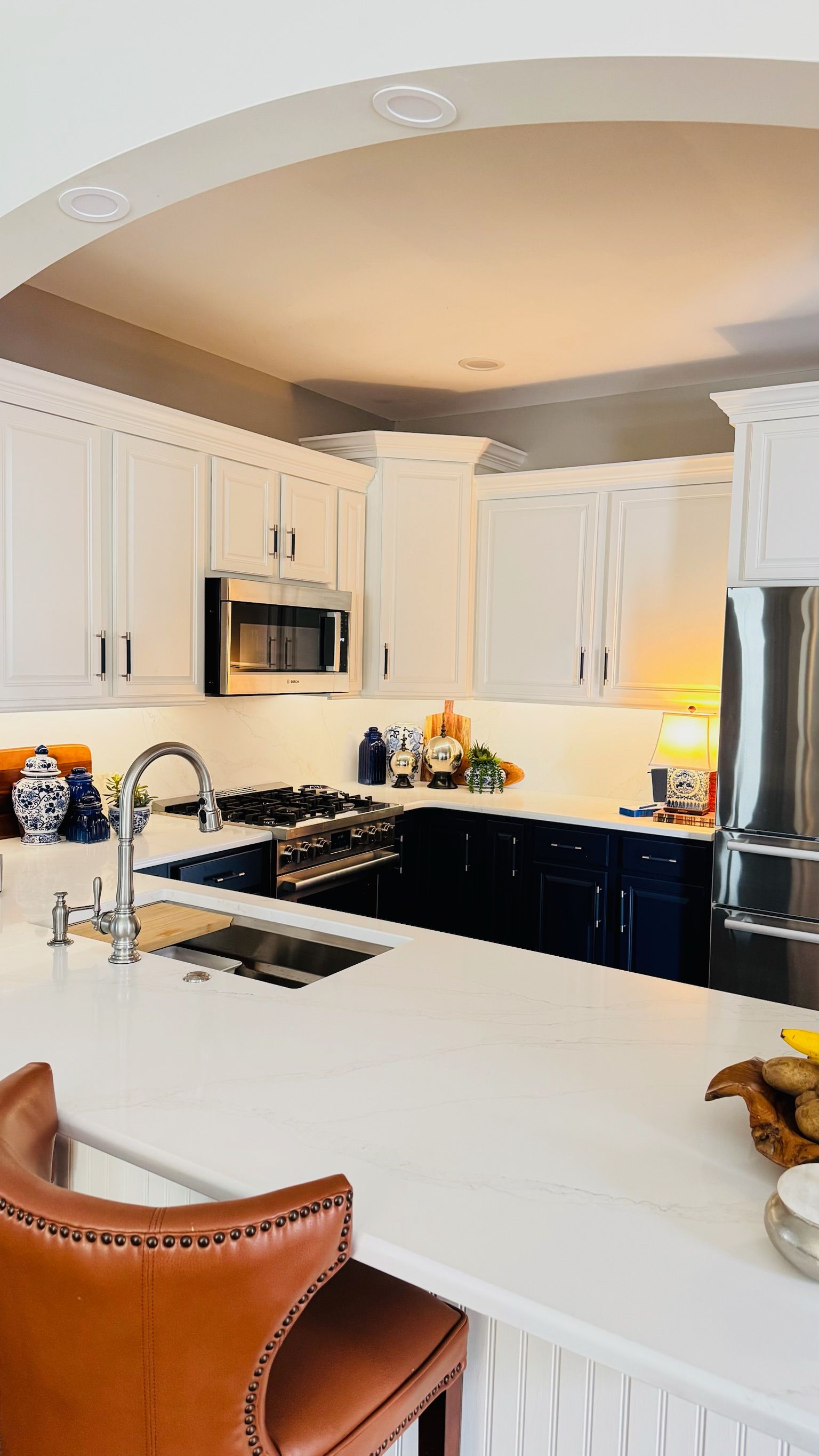 Kitchen with white upper cabinets, dark blue lower cabinets, stainless steel appliances, and a white countertop.