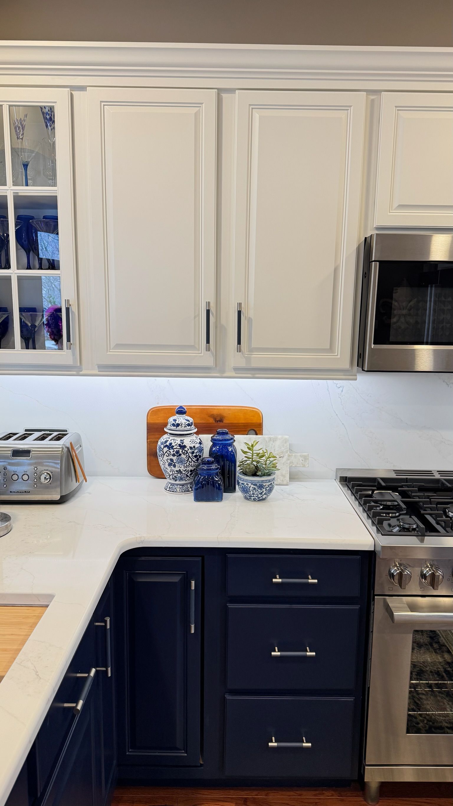 Kitchen with white upper cabinets, blue lower cabinets, white countertops, and stainless steel appliances.