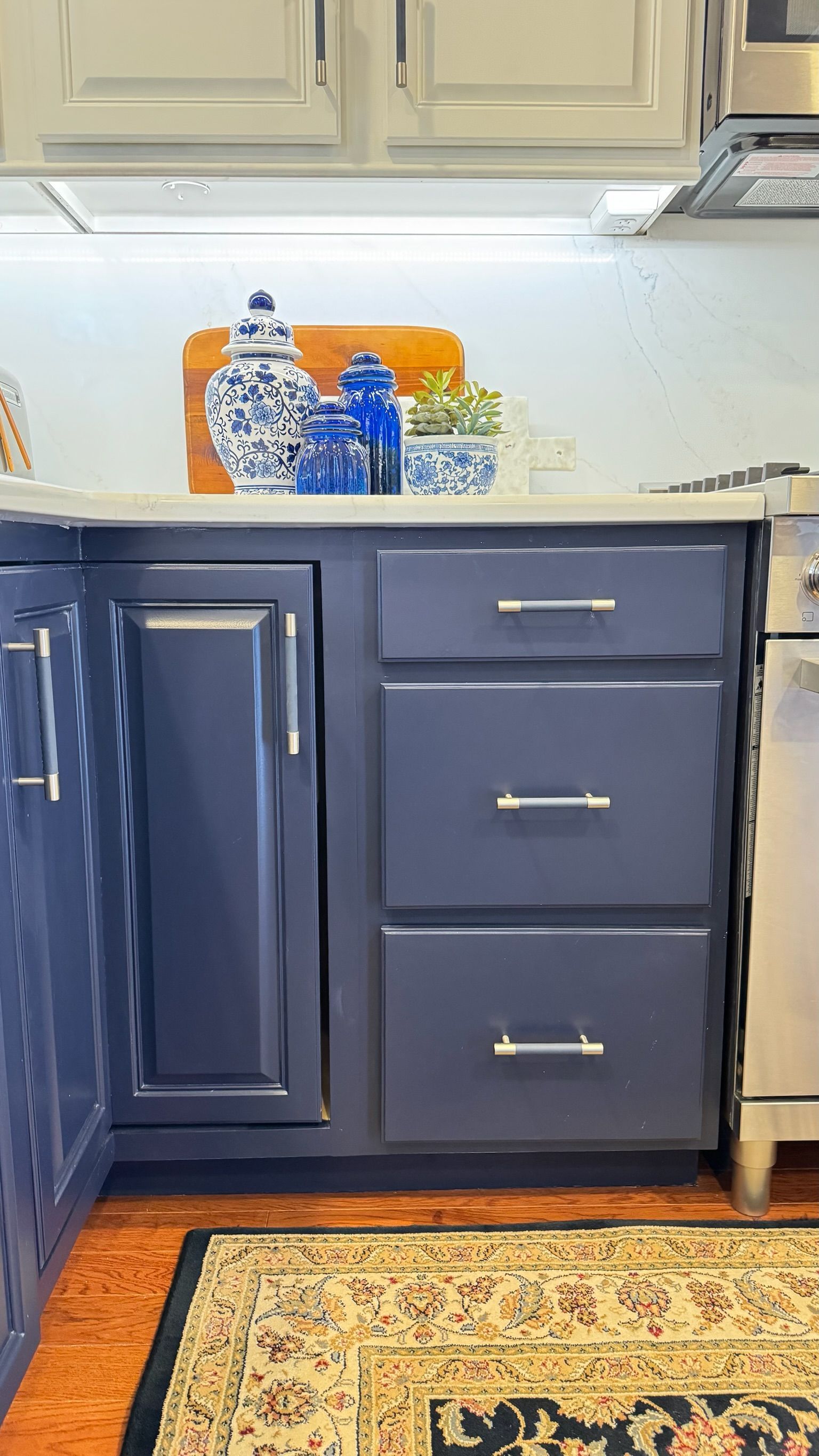 Blue kitchen cabinets with drawers, countertop decor, and hardwood floor.