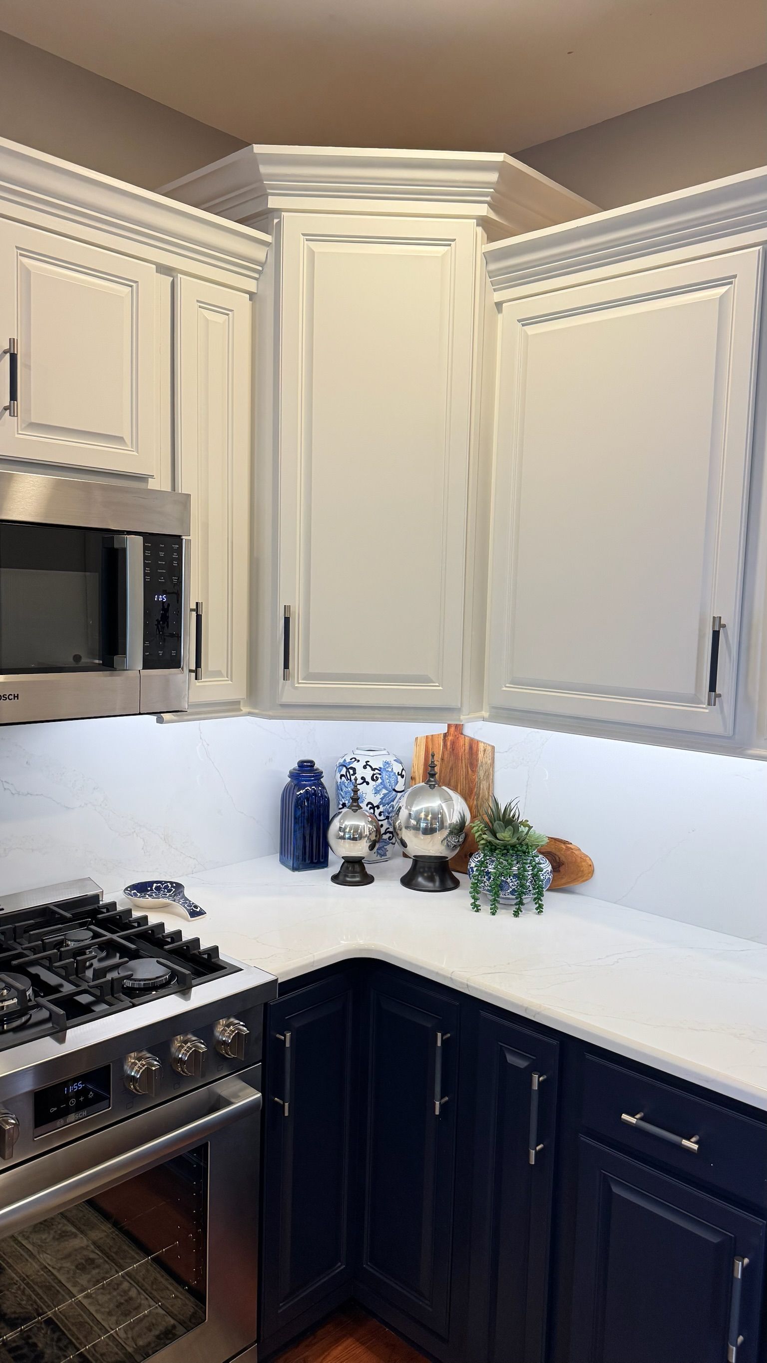 Kitchen corner with white and navy cabinets, white countertops, and decorations.