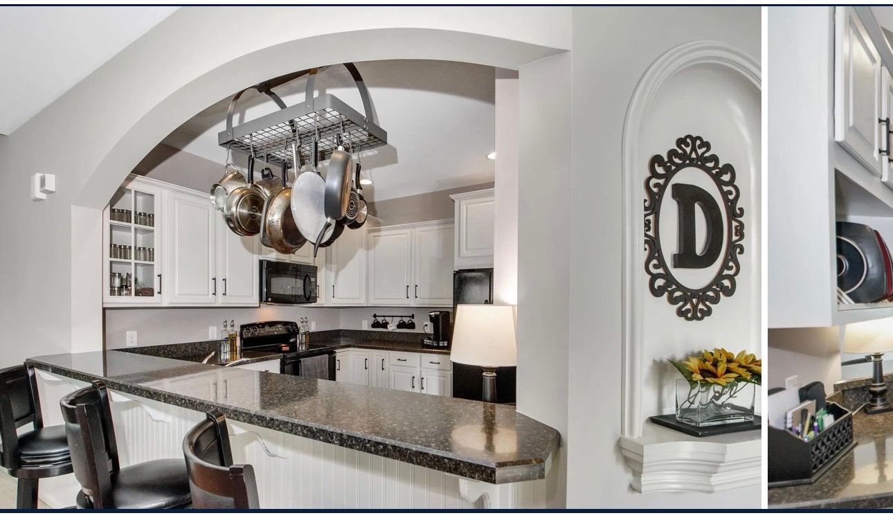 Kitchen with arched doorway, granite countertops, white cabinets, and hanging pots. Decorative niche with a 