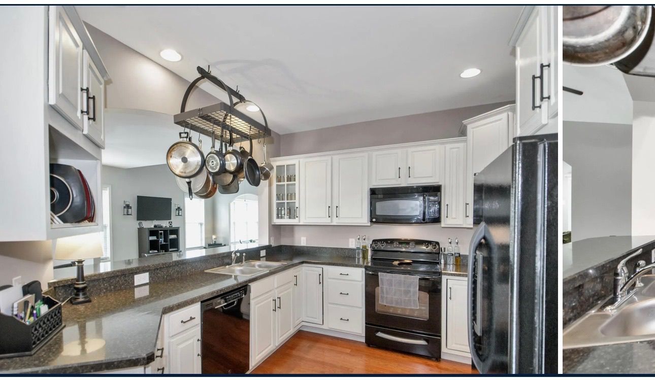 White kitchen with black appliances, granite countertops, and pot rack.