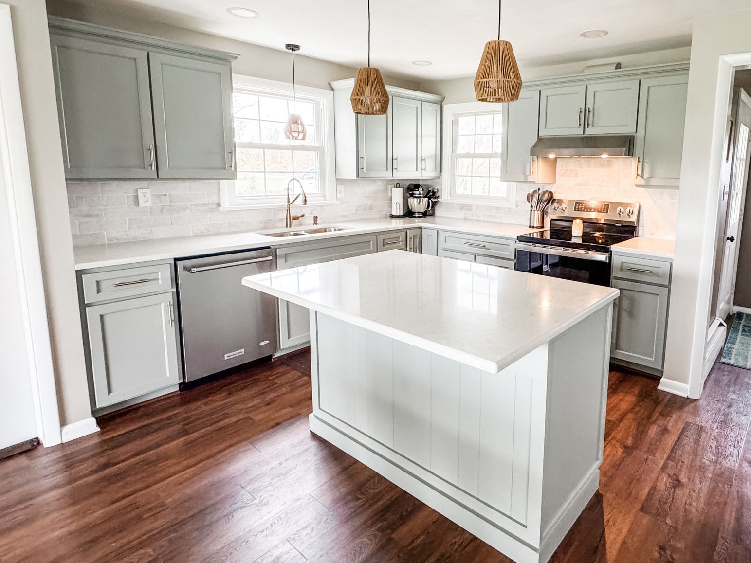 Kitchen with blue-gray cabinets, white countertops, stainless steel appliances, and wood floors.