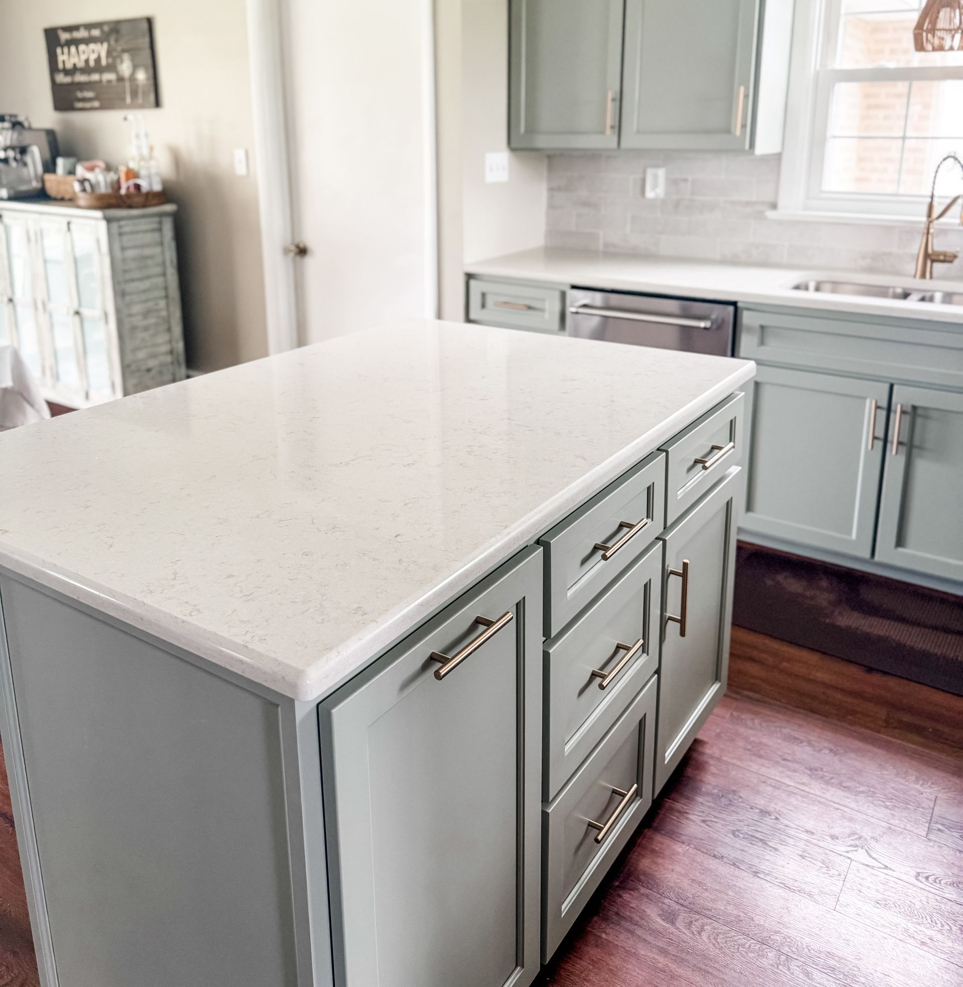 Kitchen with blue-gray cabinets, white island, dark wood floor, and woven pendant lights.