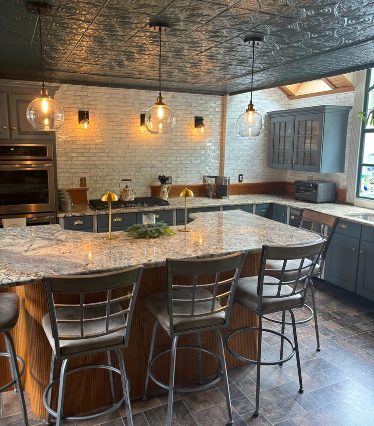 Kitchen with a large island, brick wall, gray cabinets, and pendant lights.
