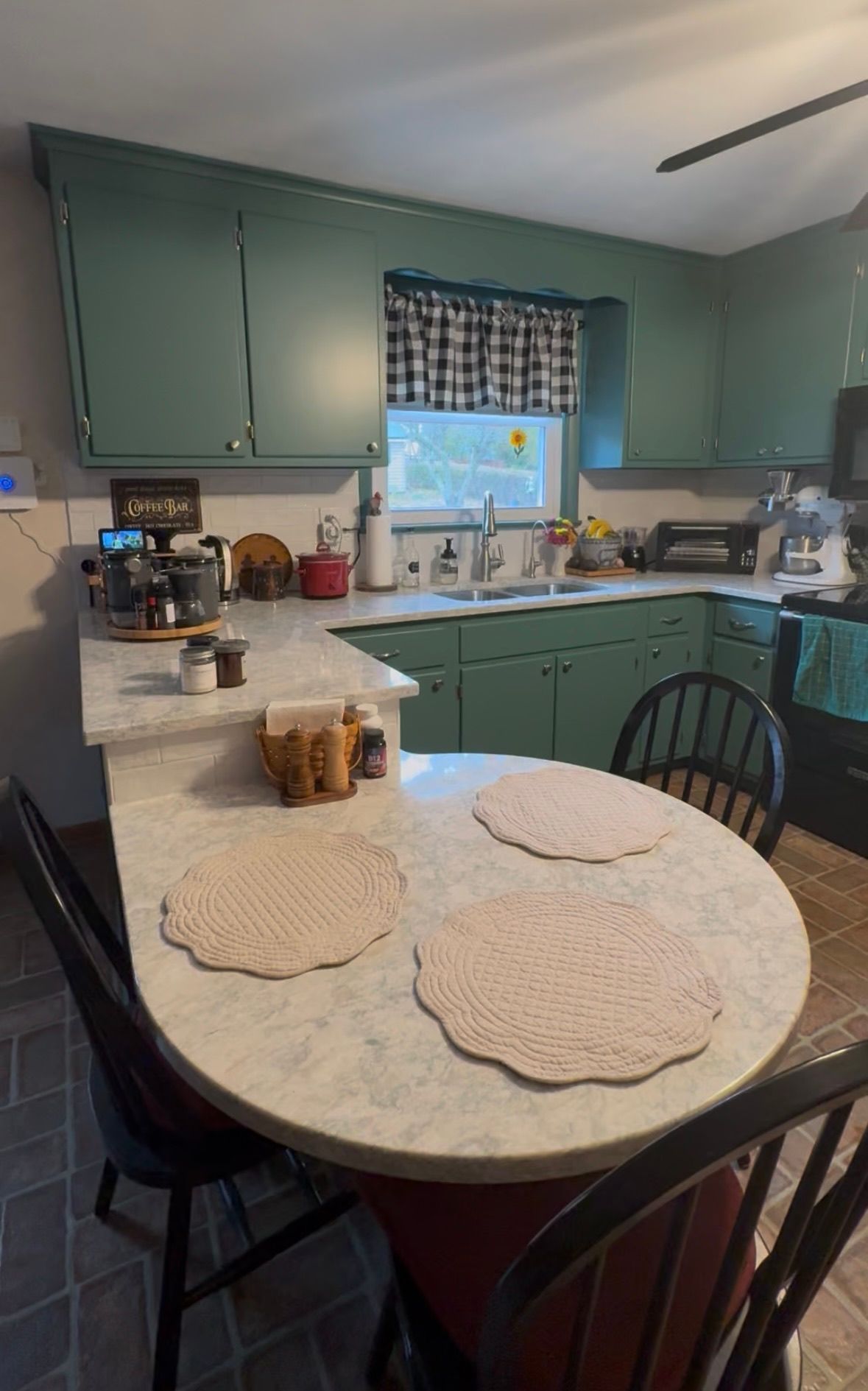 Kitchen with green cabinets, a round table with placemats, and chairs.
