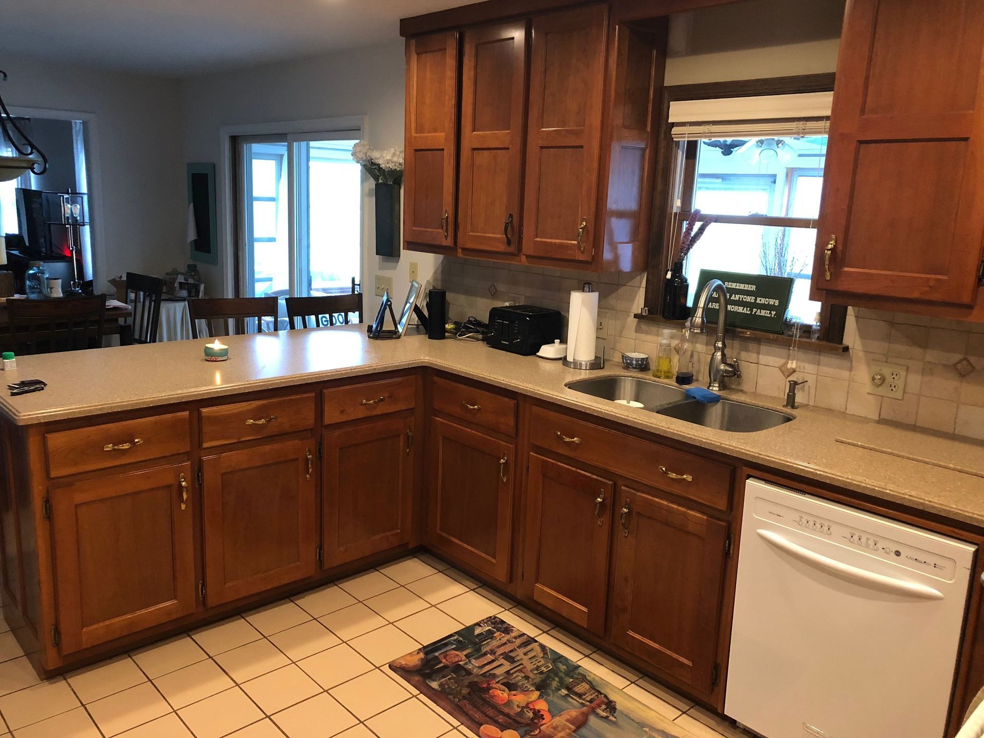 Kitchen with wooden cabinets, beige countertops, and a white dishwasher.