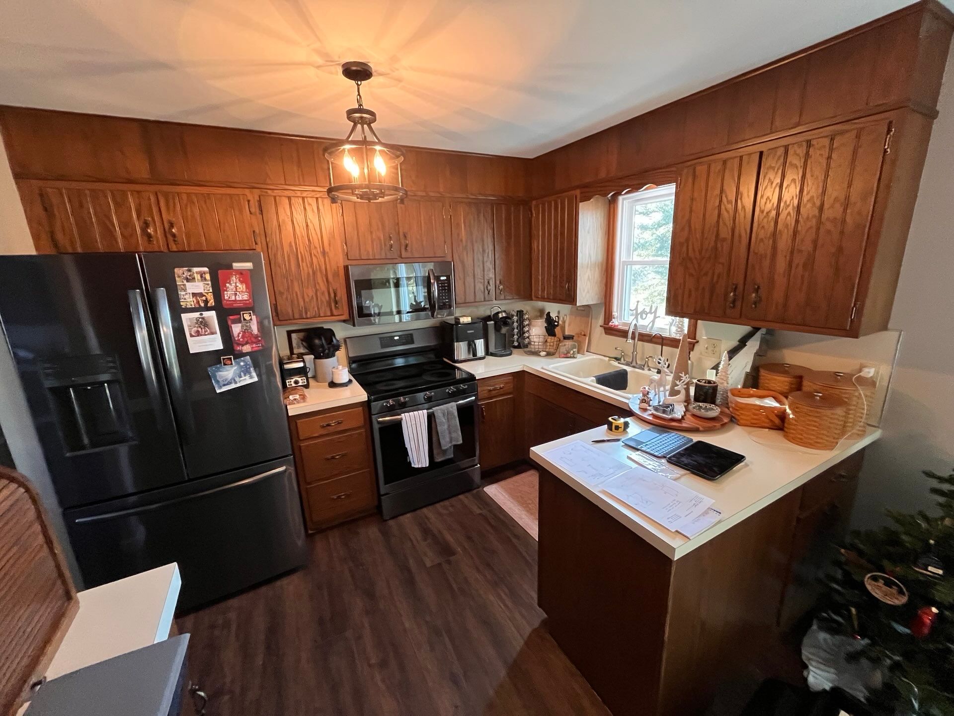 Small kitchen with dark wood cabinets, black appliances, and a window over a corner counter.