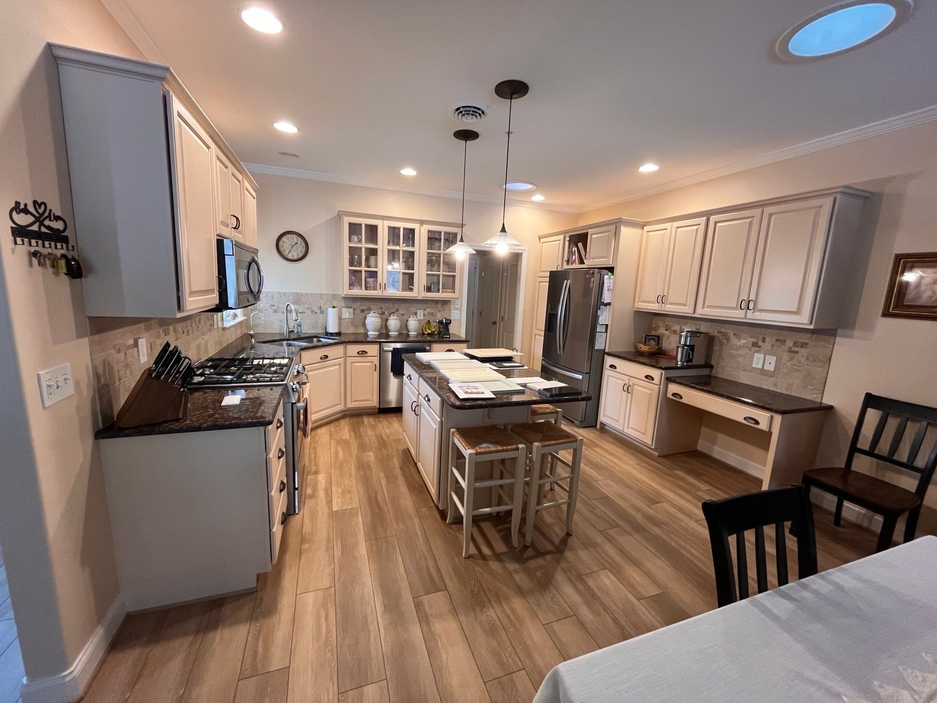 Bright modern kitchen with island, bar stools, white cabinets, and hardwood floors