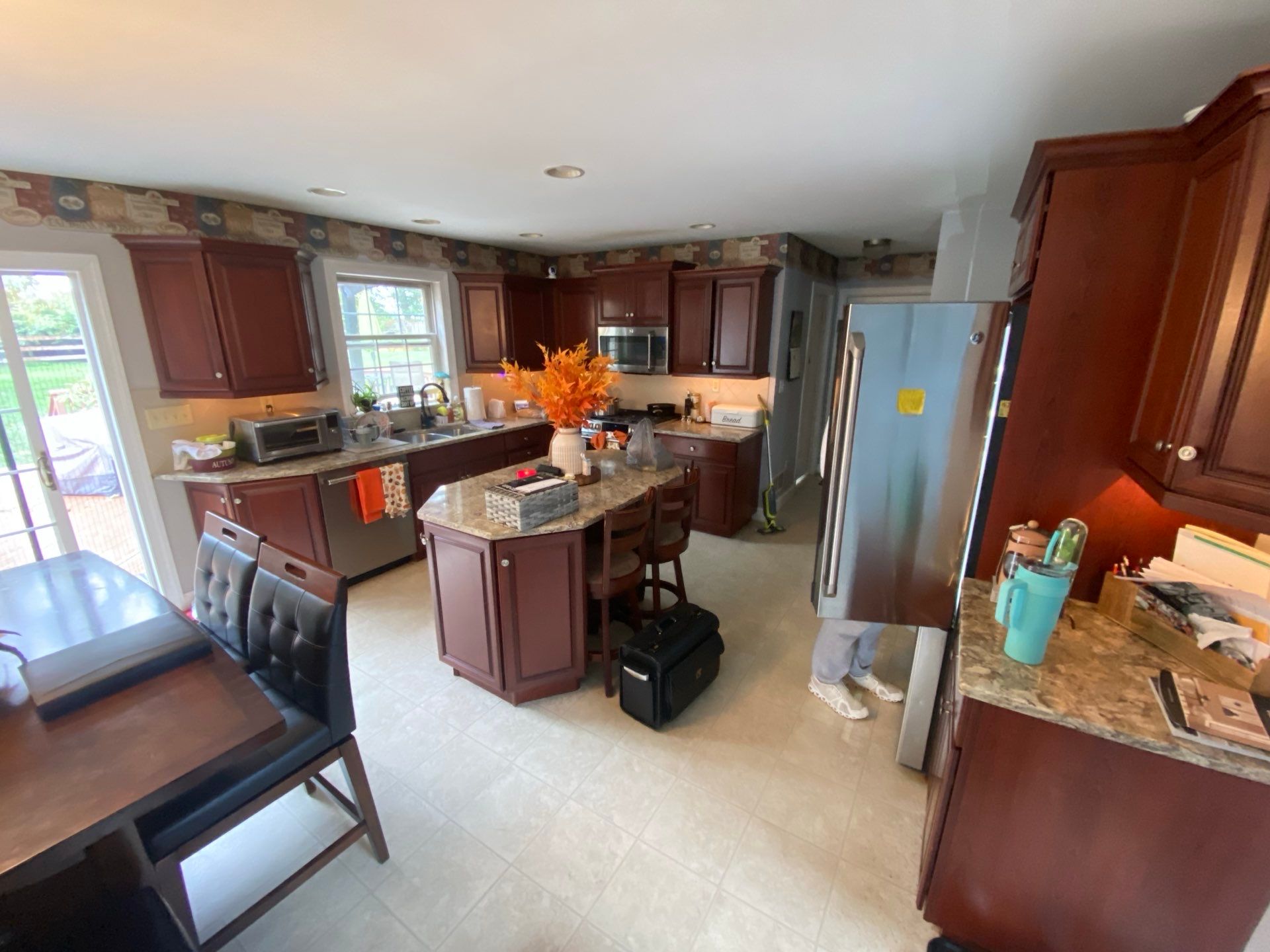 Kitchen with dark wood cabinets, stainless fridge, center island, and light tile floor