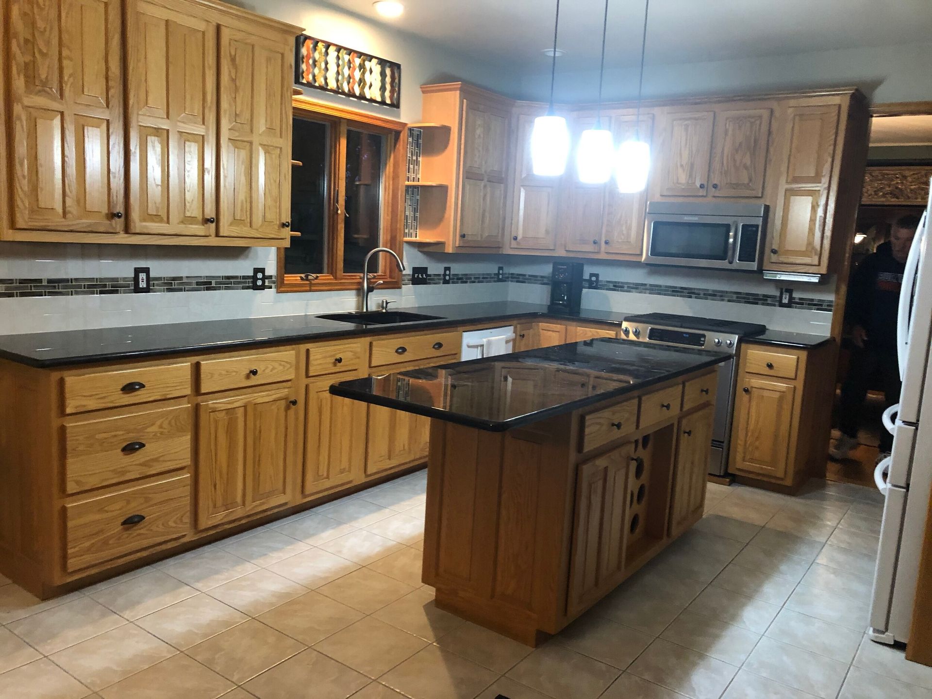 Kitchen with wooden cabinets, black countertops, and an island.
