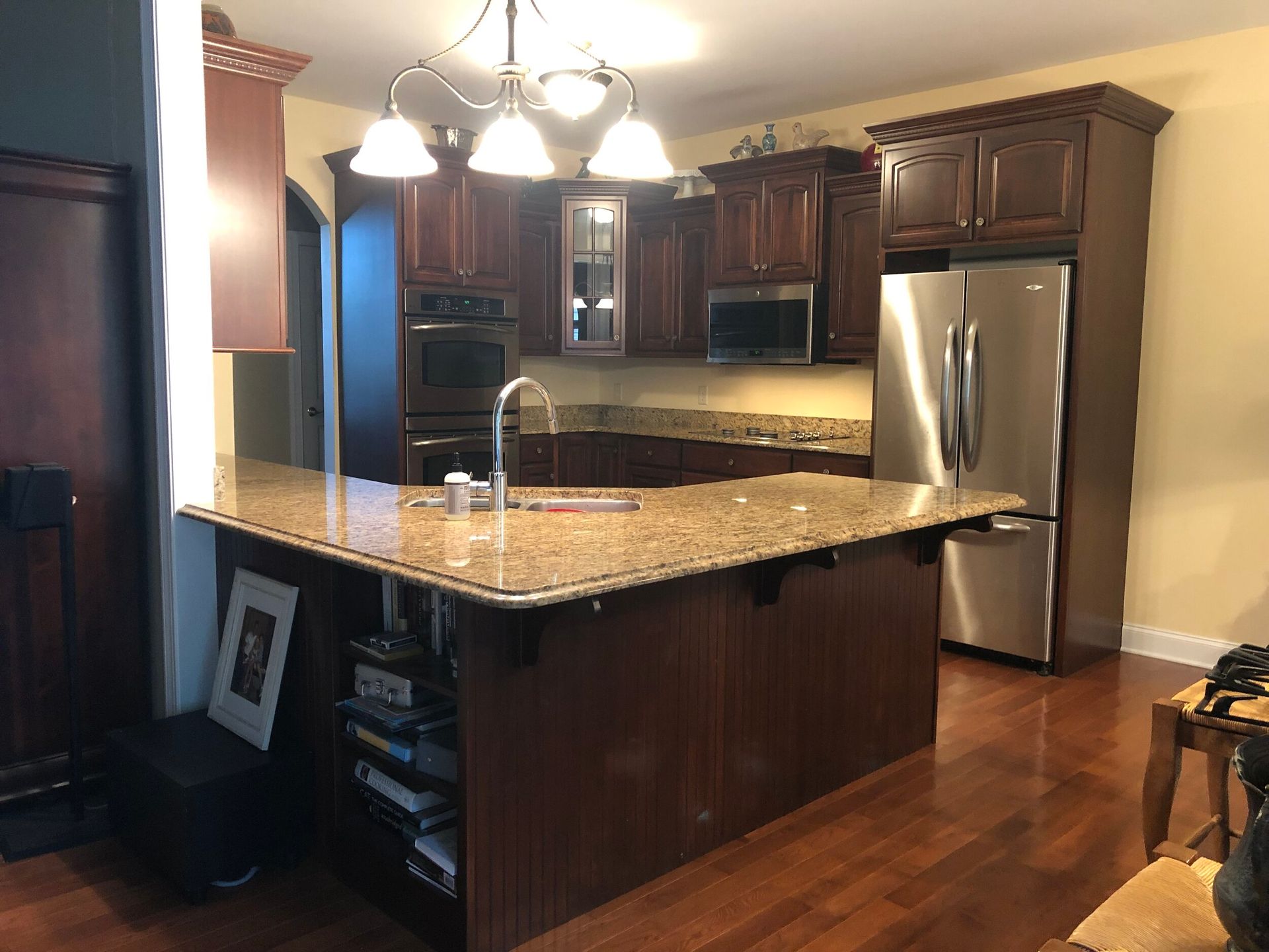 Kitchen with dark wood cabinets, granite countertops, stainless steel appliances, and a central island.