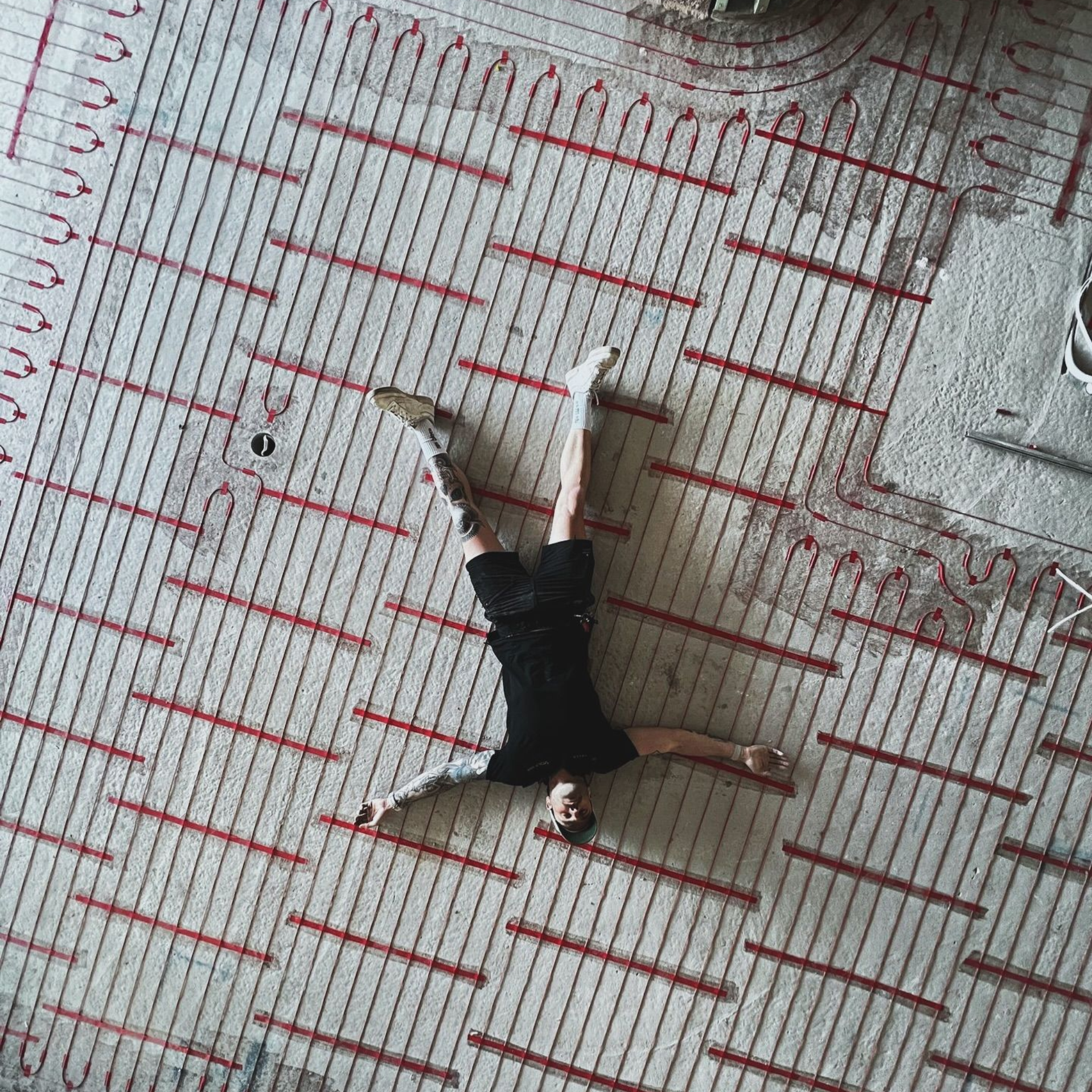 Person lying on patterned floor, arms outstretched, legs in the air.