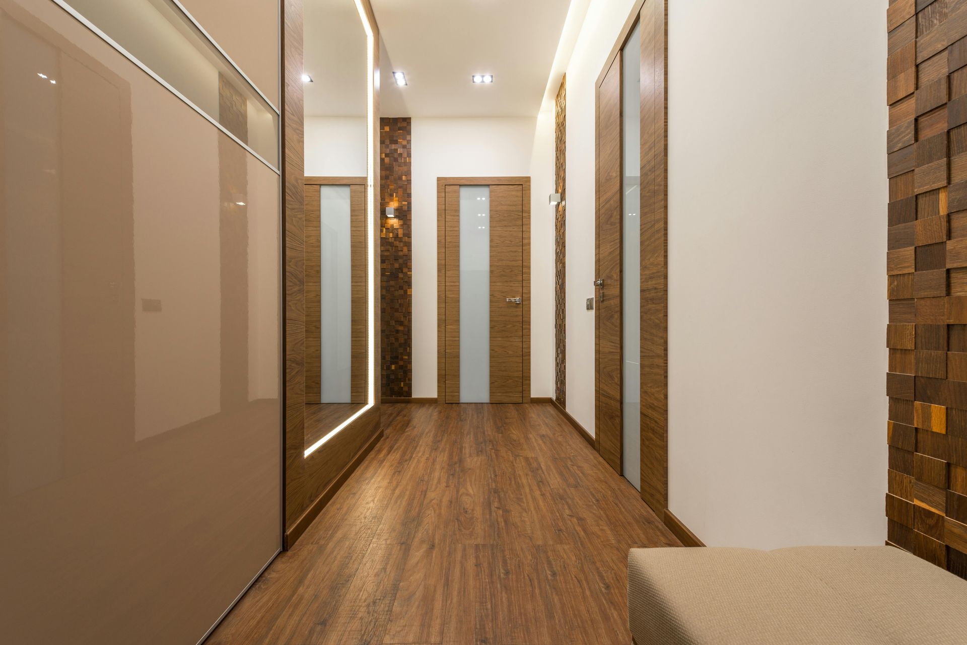 Modern hallway with wood flooring, beige walls, mirrored doors, and recessed ceiling lights
