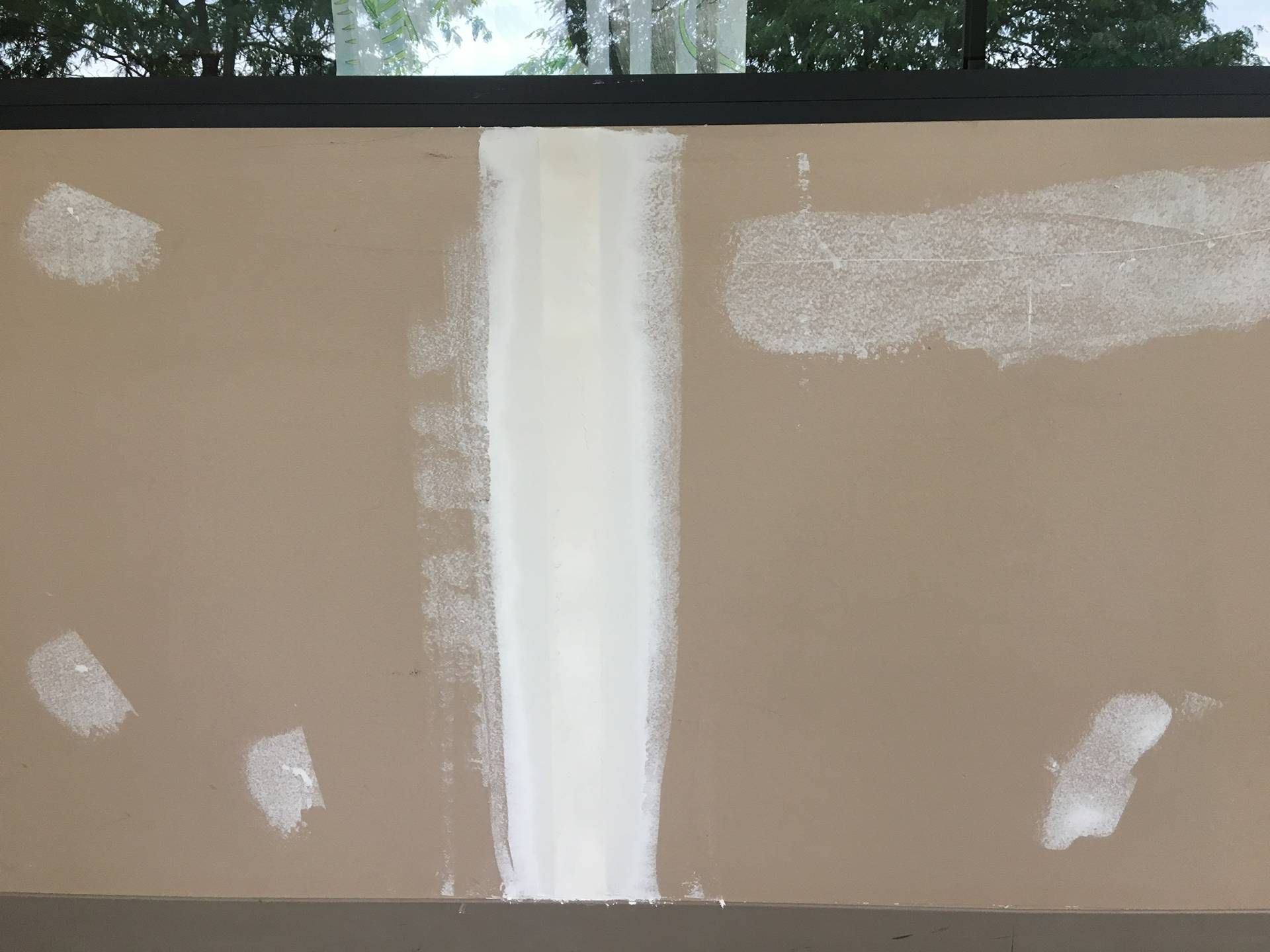 Beige wall with a vertical white stripe and white patchy paint spots near the edges.