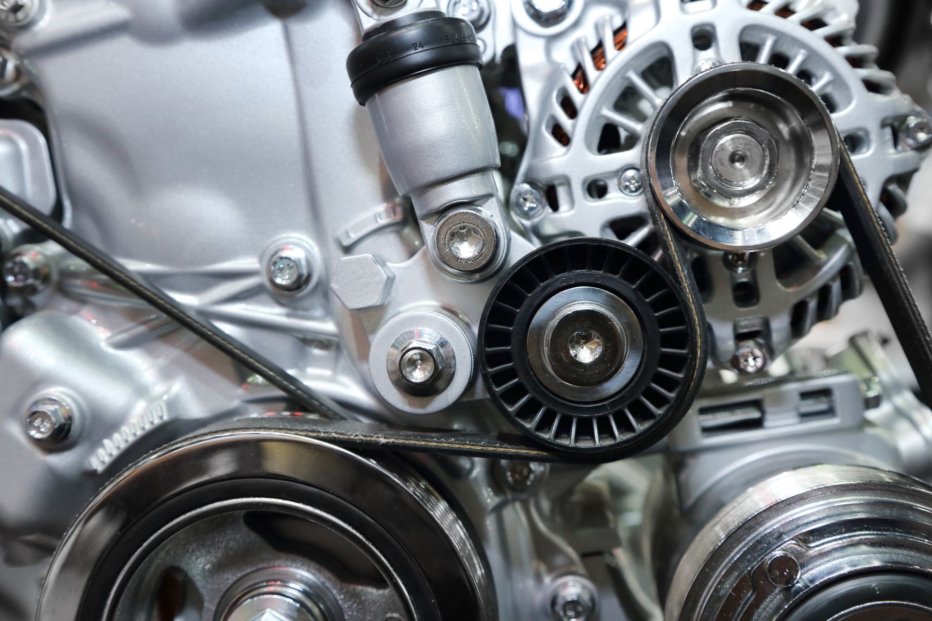 A close up of a car engine with belts and pulleys.