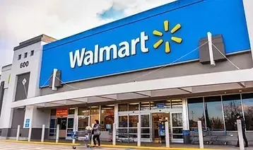 La fachada de un local de Walmart con un gran letrero azul y un logotipo de chispa amarillo brillante sobre la entrada.
