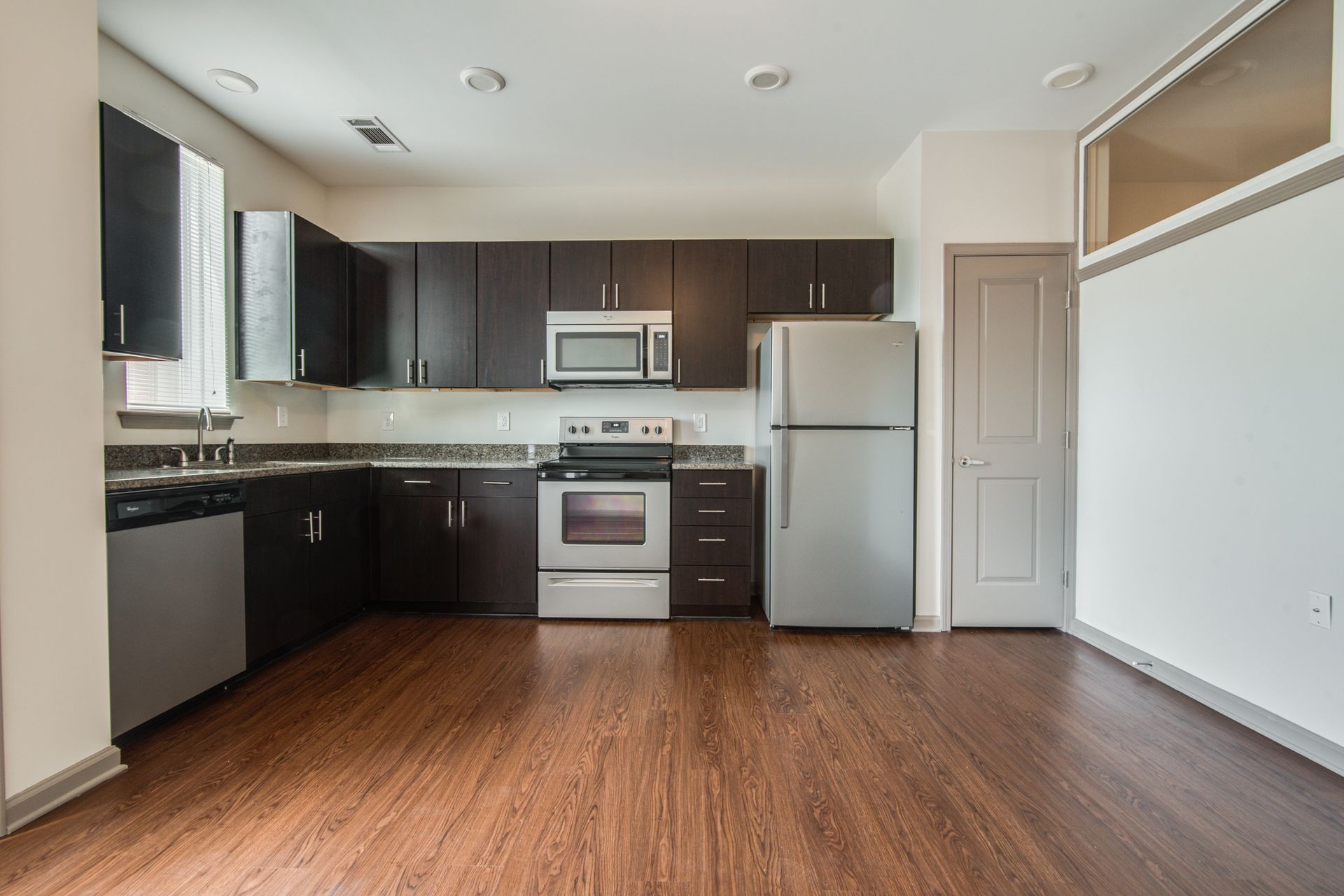 Modern kitchen with dark cabinets, stainless steel appliances, and wood flooring at Marvel Apartments.