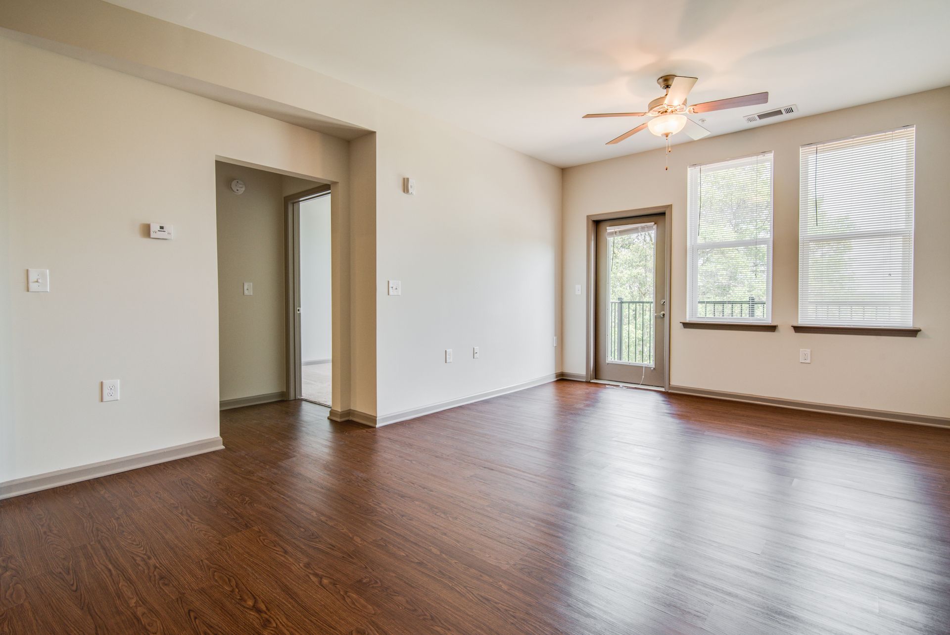 Empty living room with hardwood floors, a doorway, and a balcony door at Marvel Apartments.